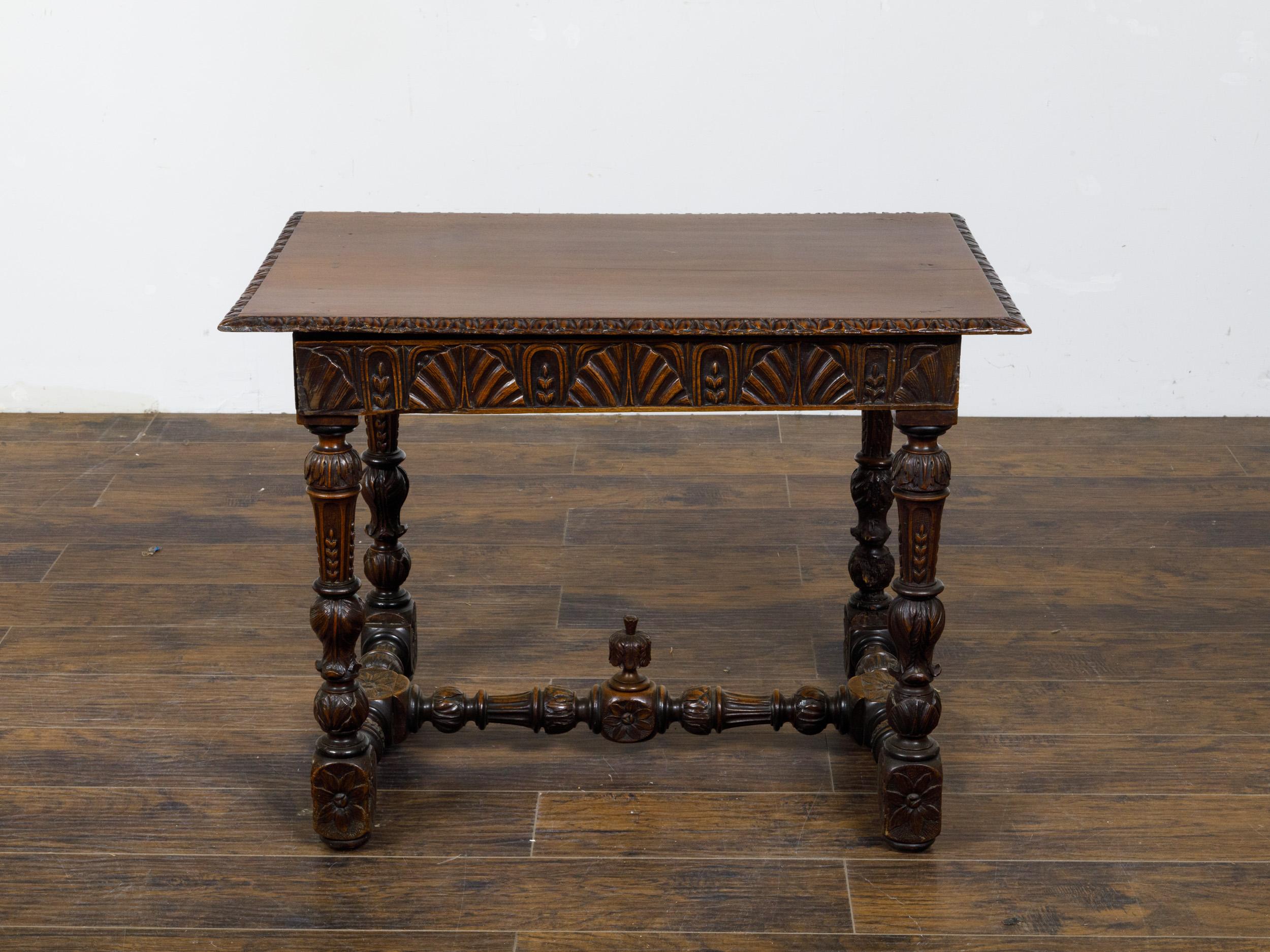 A French walnut side table from the 19th century with carved apron and H-Form cross stretcher. Introducing this magnificent 19th-century French walnut side table, a piece that epitomizes the fine craftsmanship and elaborate detailing of its time.