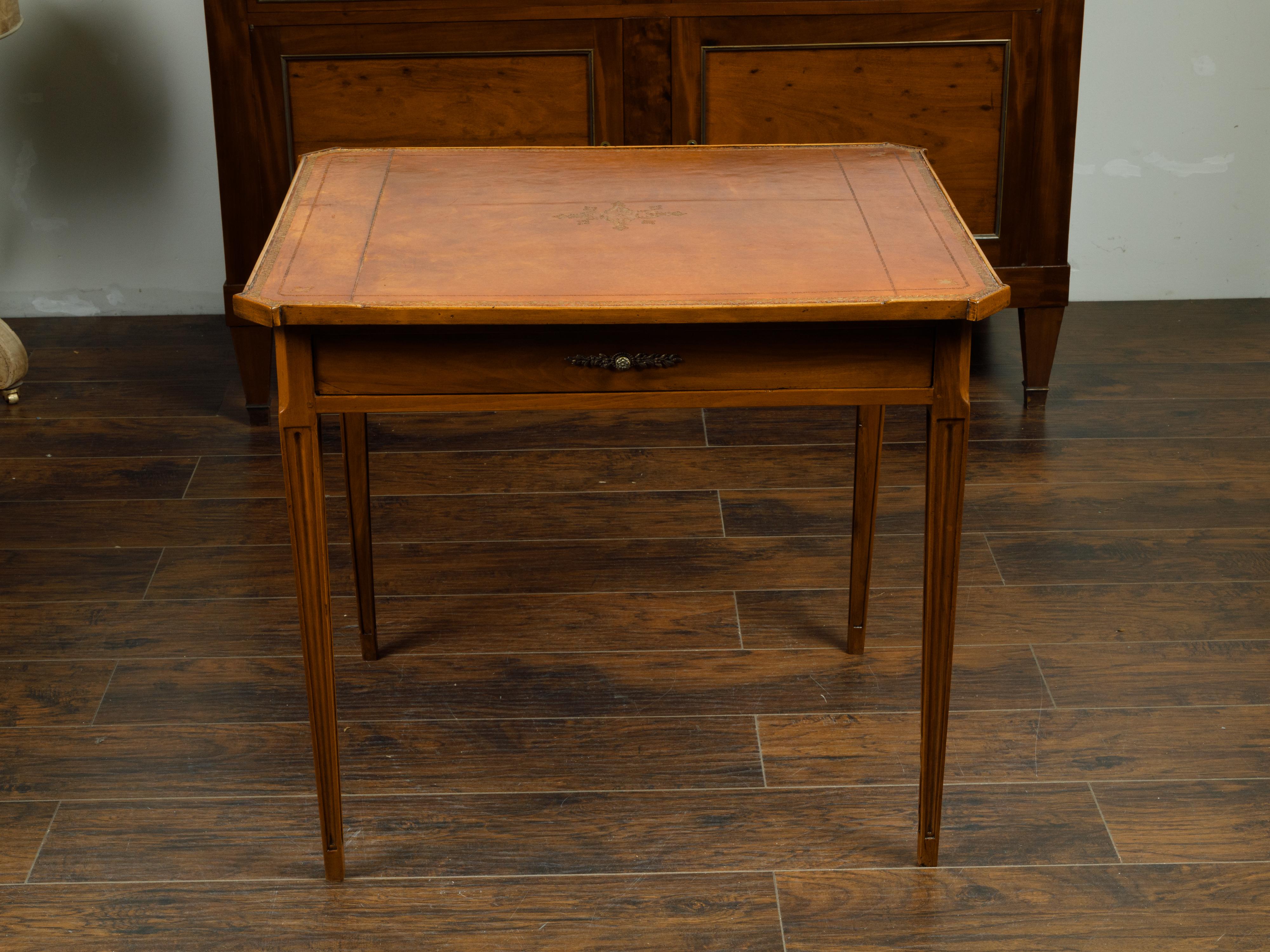 A French walnut side table from the 19th century, with gilt embossed leather top, single drawer and fluted motifs. Created in France during the 19th century, this side table features a rectangular brown leather top with gilt embossed motifs and