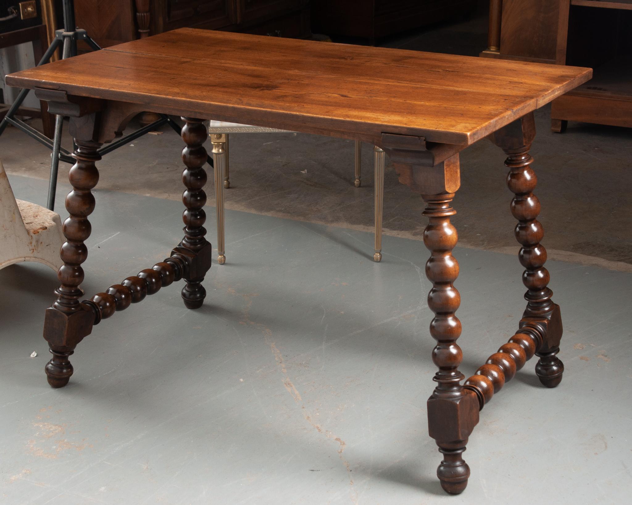 A handsome solid walnut table from 19th century France. The sturdy top is constructed of two wide bordes, connecting to a simply carved apron. The Spanish influenced turned legs are the focal point of the table, rich and deeply patinated.Quality