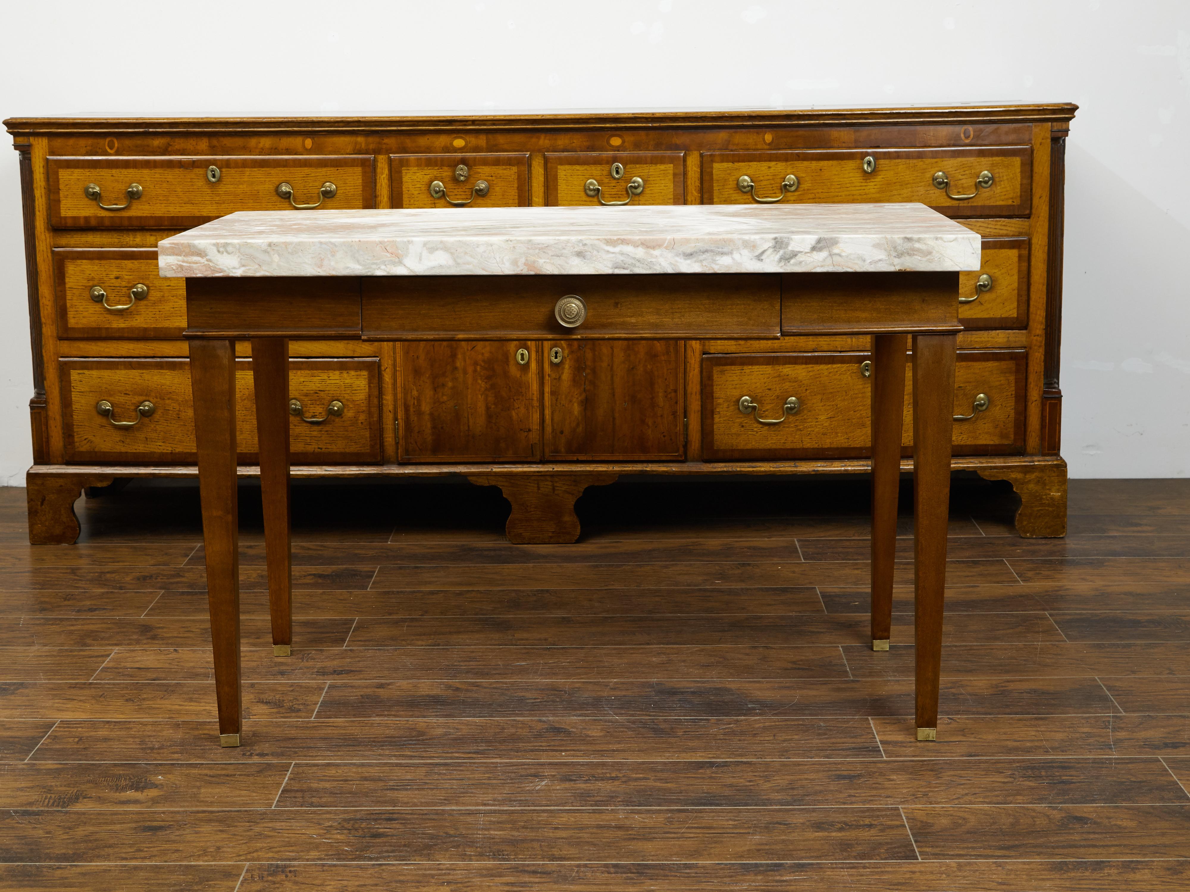 A French walnut table from the 19th century, with marble top and single drawer. Created in France during the 19th century, this walnut table features a rectangular variegated marble top sitting above a single drawer fitted with a circular brass