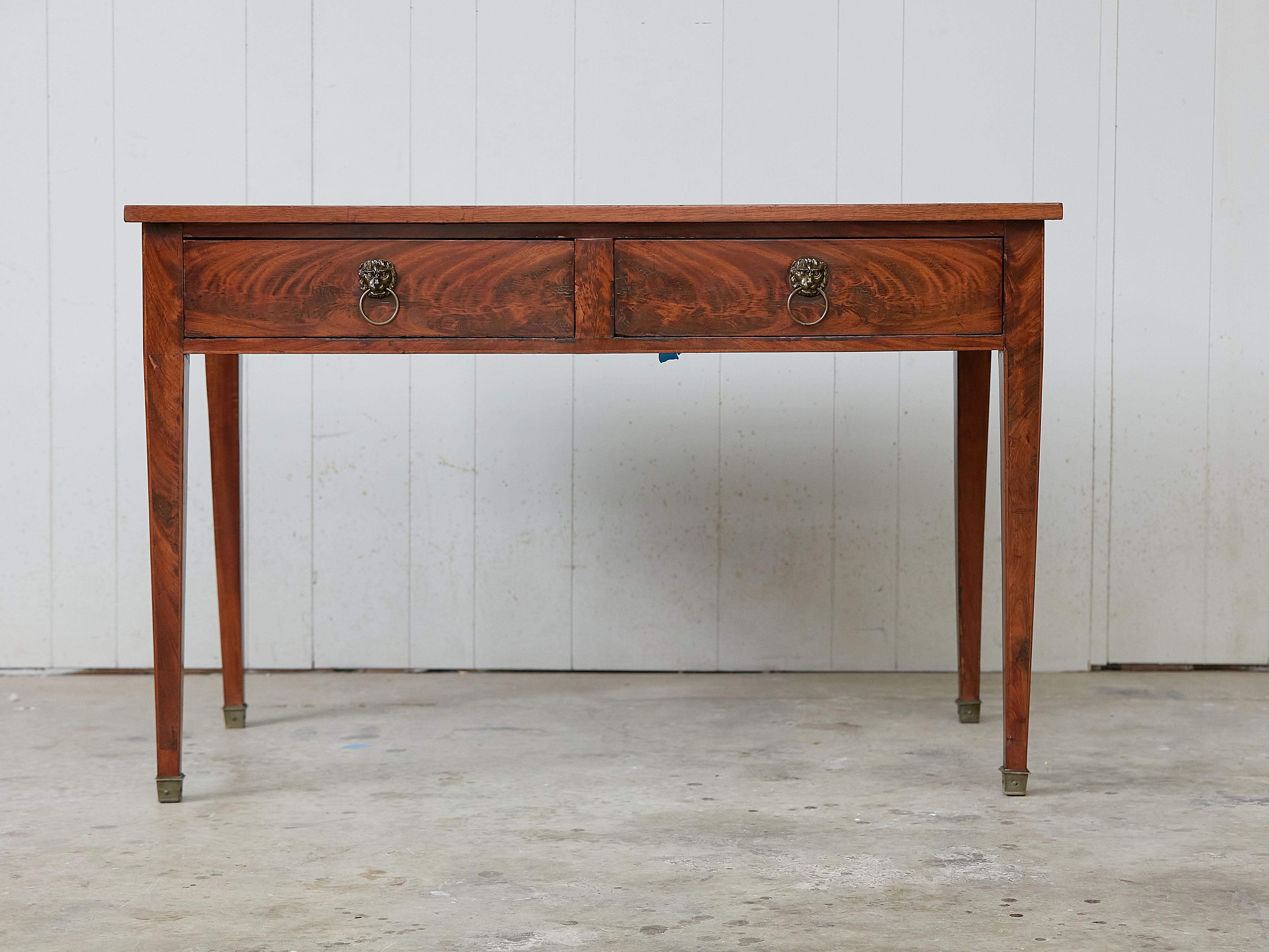 A French walnut desk from the 19th century, with leather top, two drawers and lion ring pulls. Created in France during the 19th century, this walnut desk features a rectangular top with black leather insert, sitting above two drawers fitted with