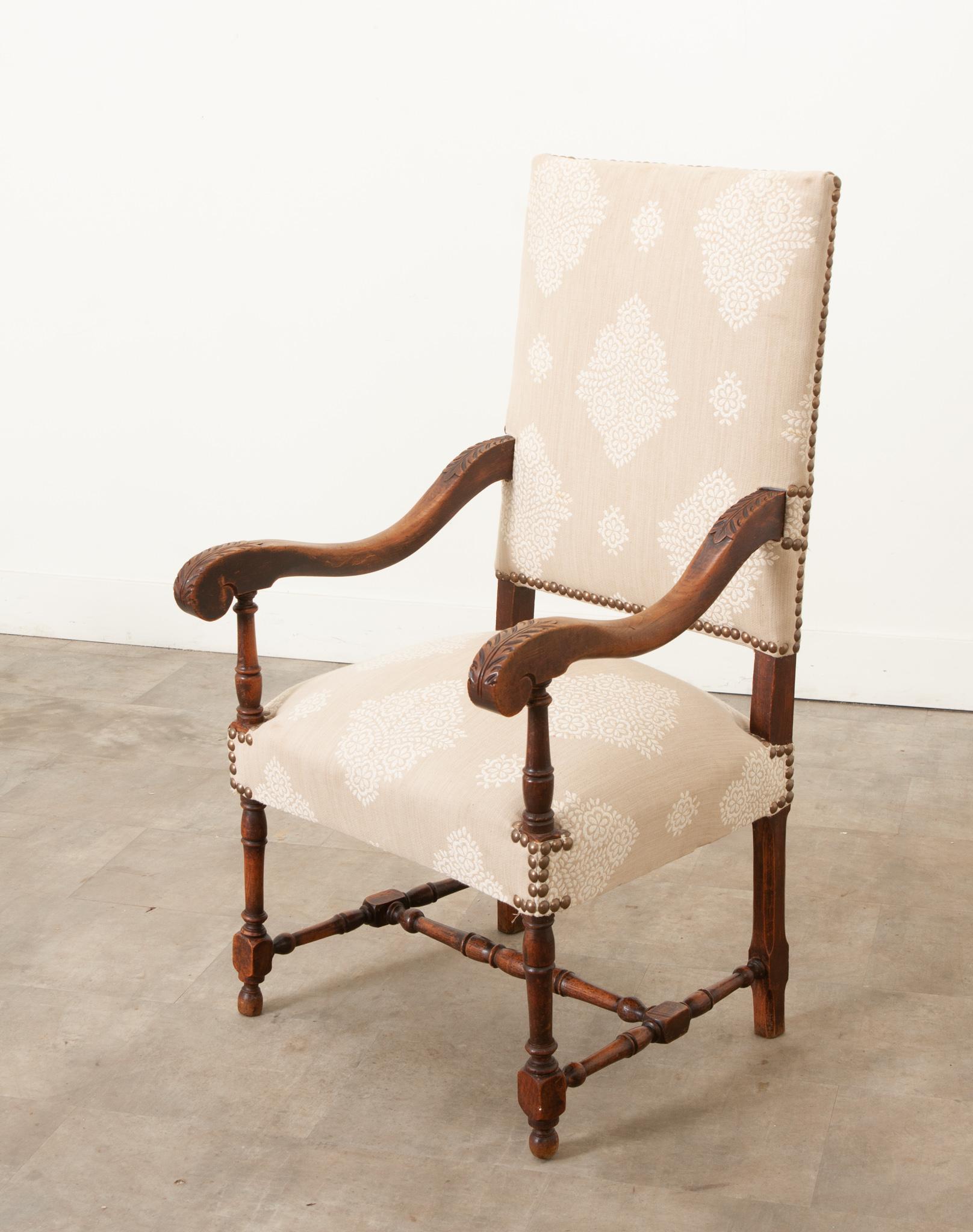 Il fauteuil francese in noce intagliato del 1800 è in splendide condizioni d'epoca. La struttura è solida e di recente è stata rivestita con un tessuto dalla fantasia rilassante circondato da punte di chiodi. Questa sedia è molto comoda e facile da