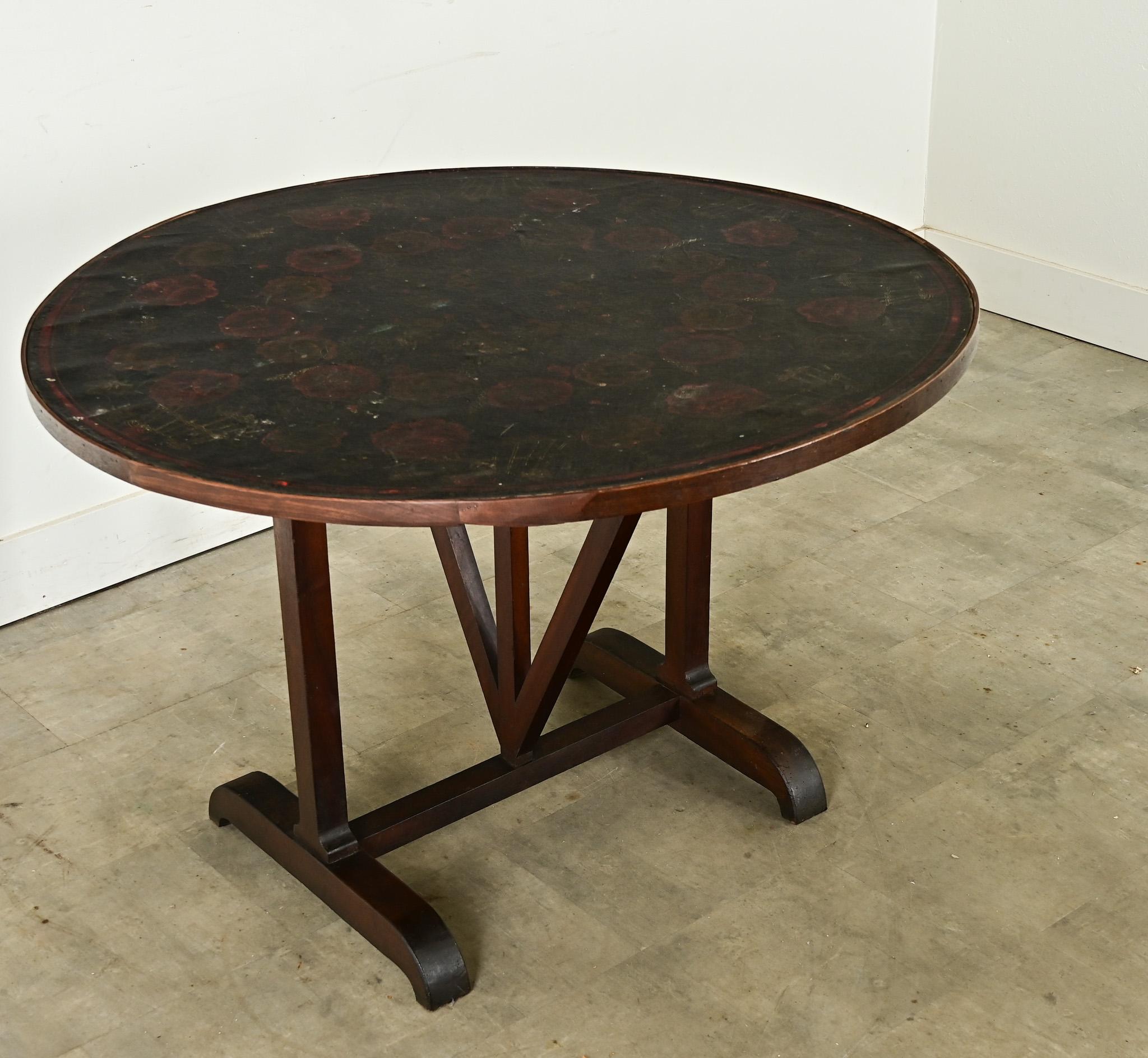 Cette table de dégustation de vin, connue sous le nom de vendange, a été fabriquée à la fin du XIXe siècle en France par un procédé créatif consistant à envelopper une toile peinte sur les planches de noyer afin de créer une finition tactile mais