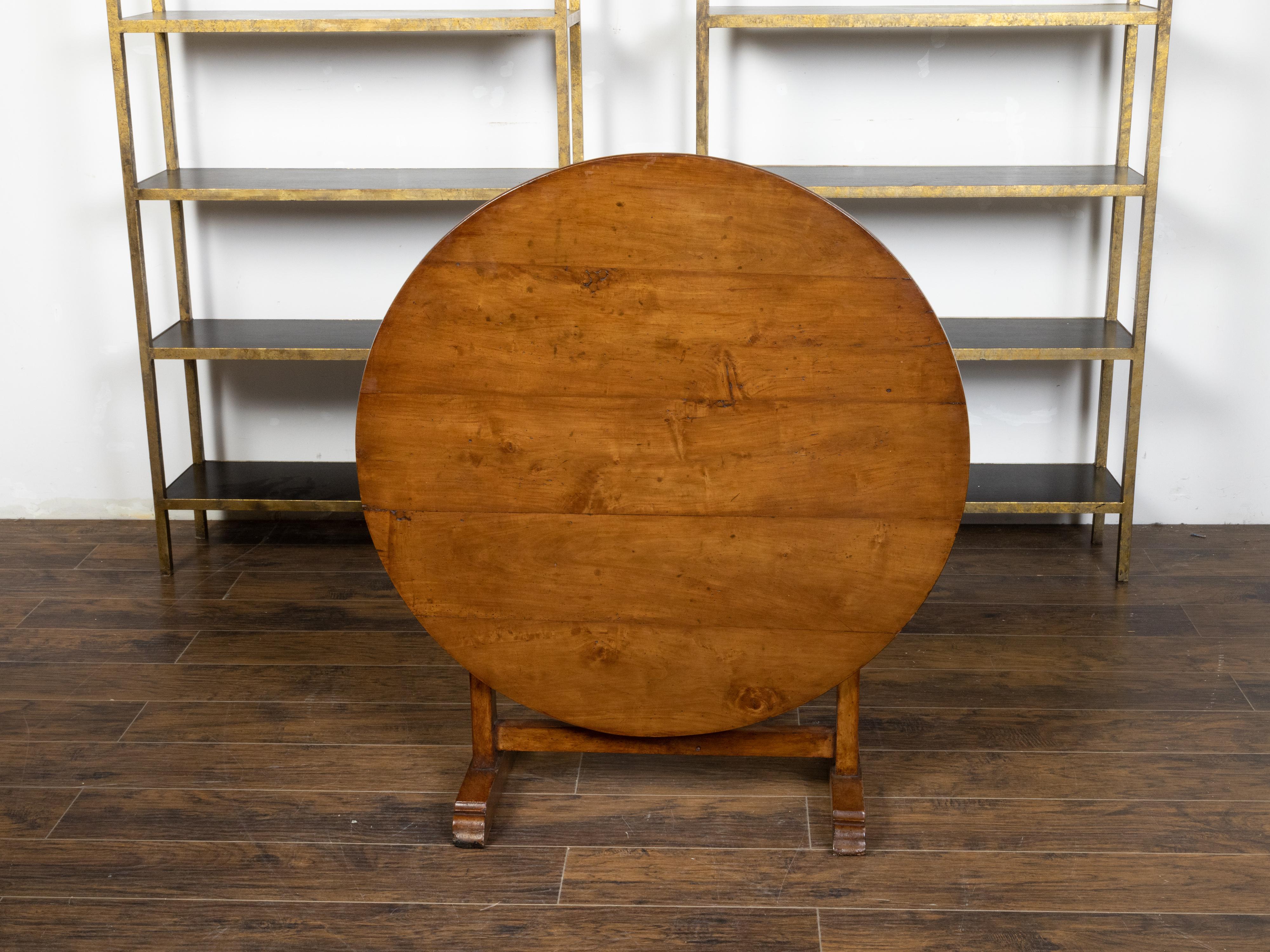 A French walnut wine tasting table from the 19th century, with circular top, trestle base and turning butterfly wedge. Created in France during the politically dynamic 19th century, this rustic walnut wine tasting table features a round planked