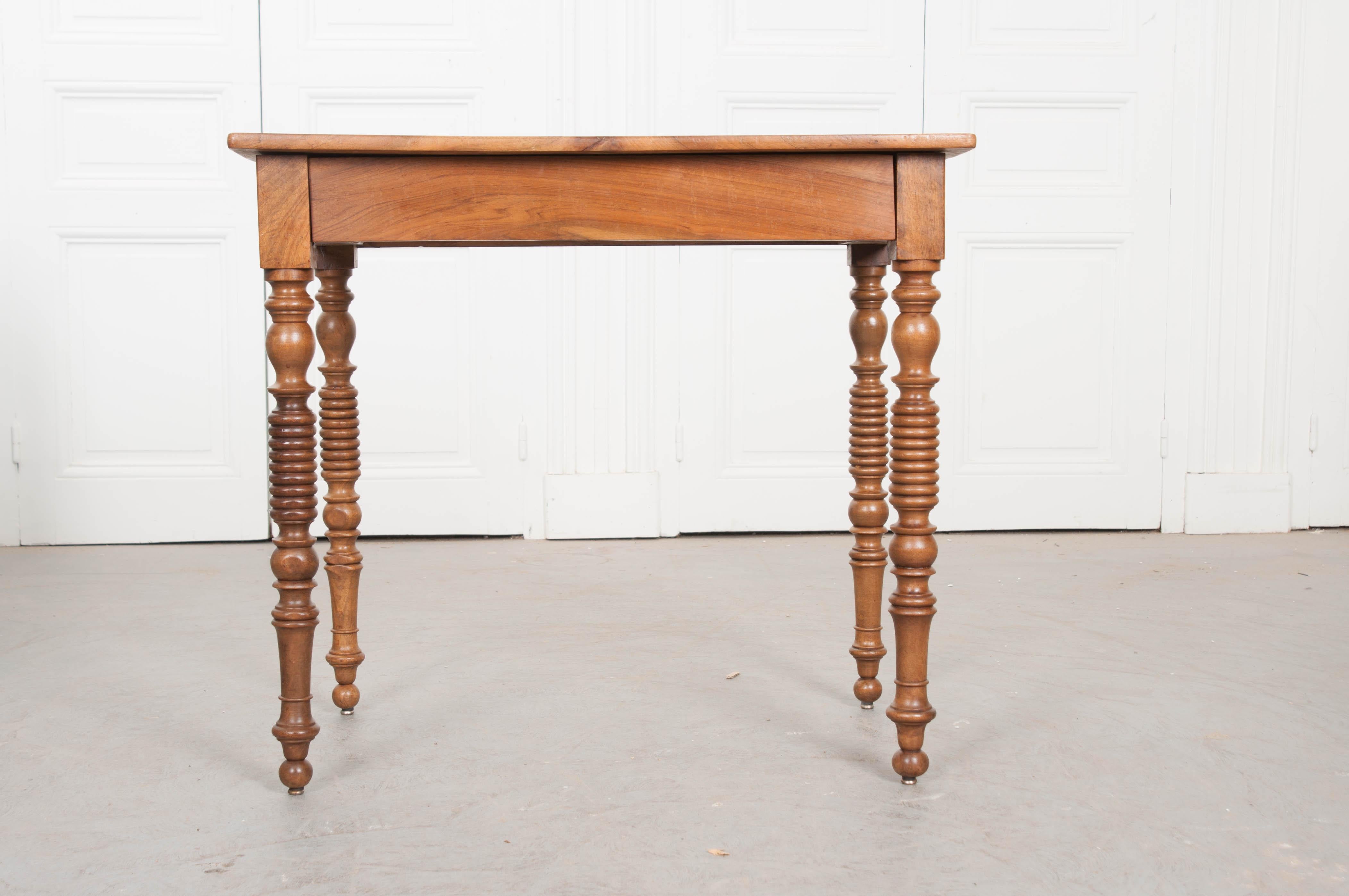 A friendly little walnut writing table from 1880's France. This exceptional little desk has been made using beautiful, solid walnut. Within the apron resides a hidden drawer that can accommodate storage for pens, paper, stationary and various
