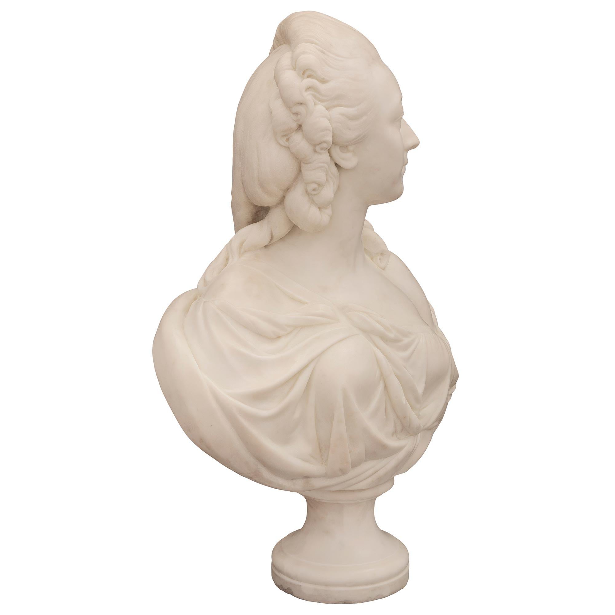 An elegant French 19th century white Carrara marble bust of La Comtesse Du Bary in the manner of Augustin Pajou. The bust is raised by a fine circular socle shaped pedestal support with a lovely mottled band. The Contesse is draped in classical
