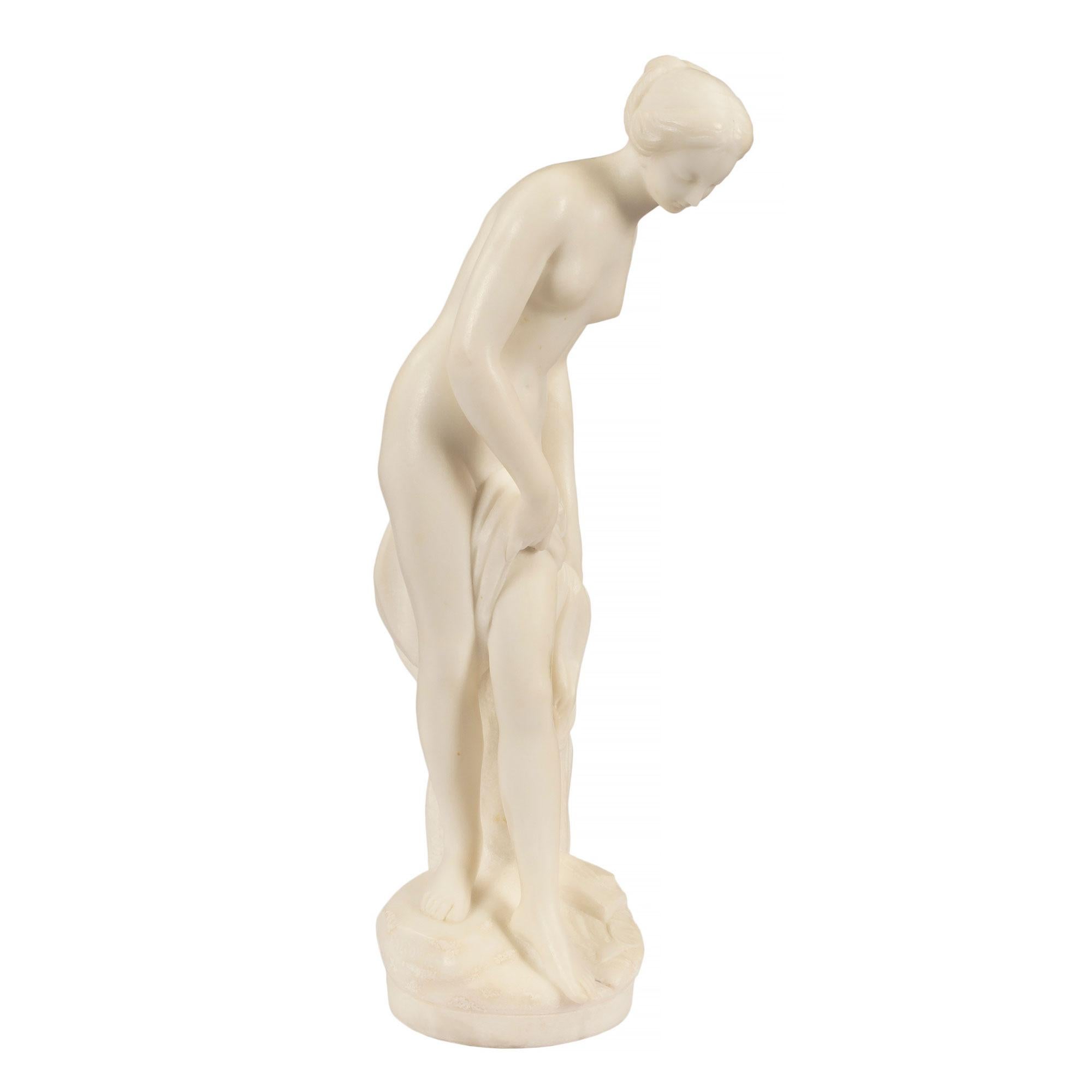 An elegant and well sculpted French 19th century white Carrara marble statue of 'La Baigneuse', bathing lady after the original by Falconet. The statue depicts a young lady about to to dip her toes into the water while holding a towel. Fine detail