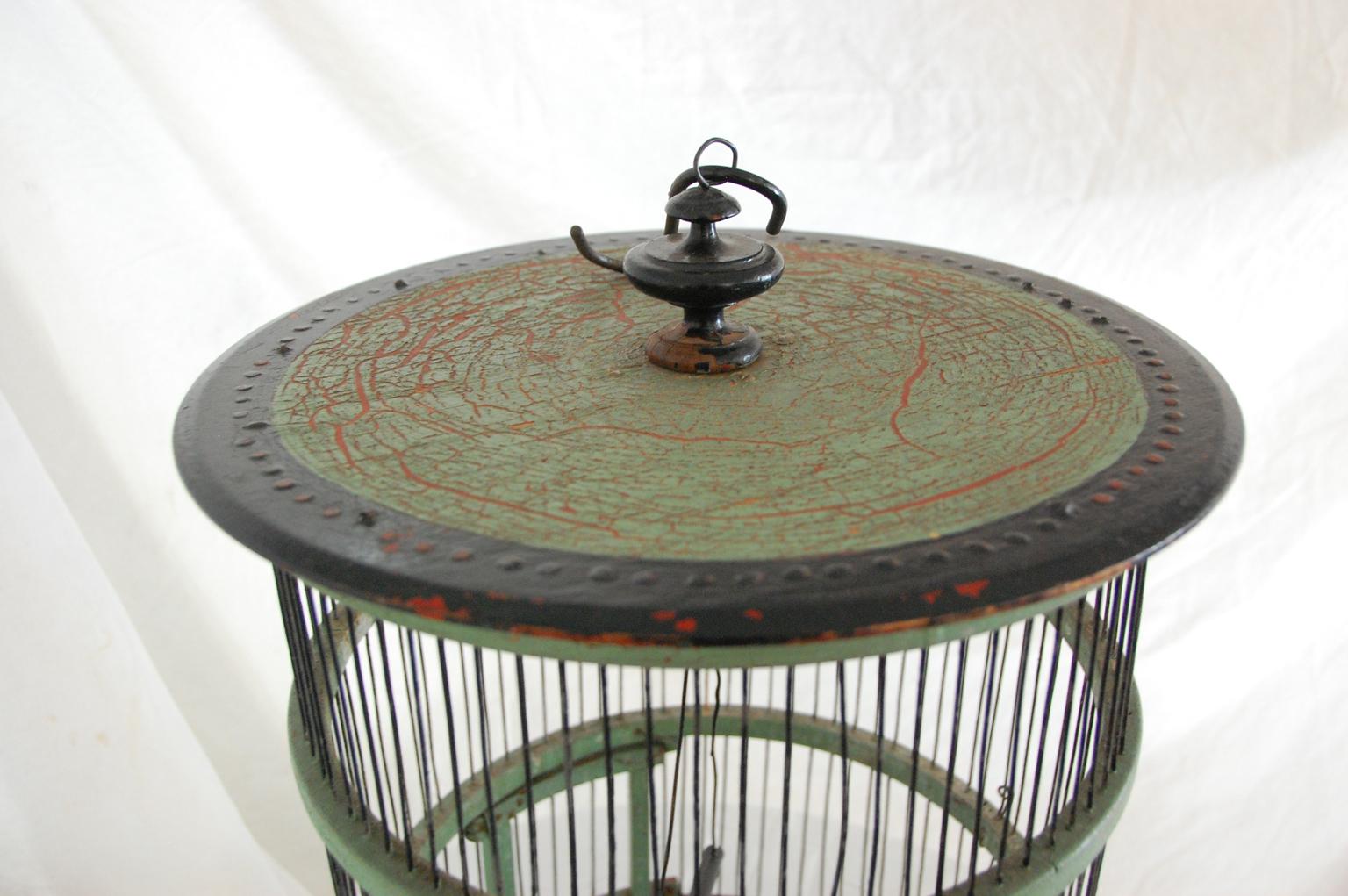 French 19th century painted green wood and wire birdcage of round form, with external protrusions for food and perching and internal swinging perch, late 19th century.