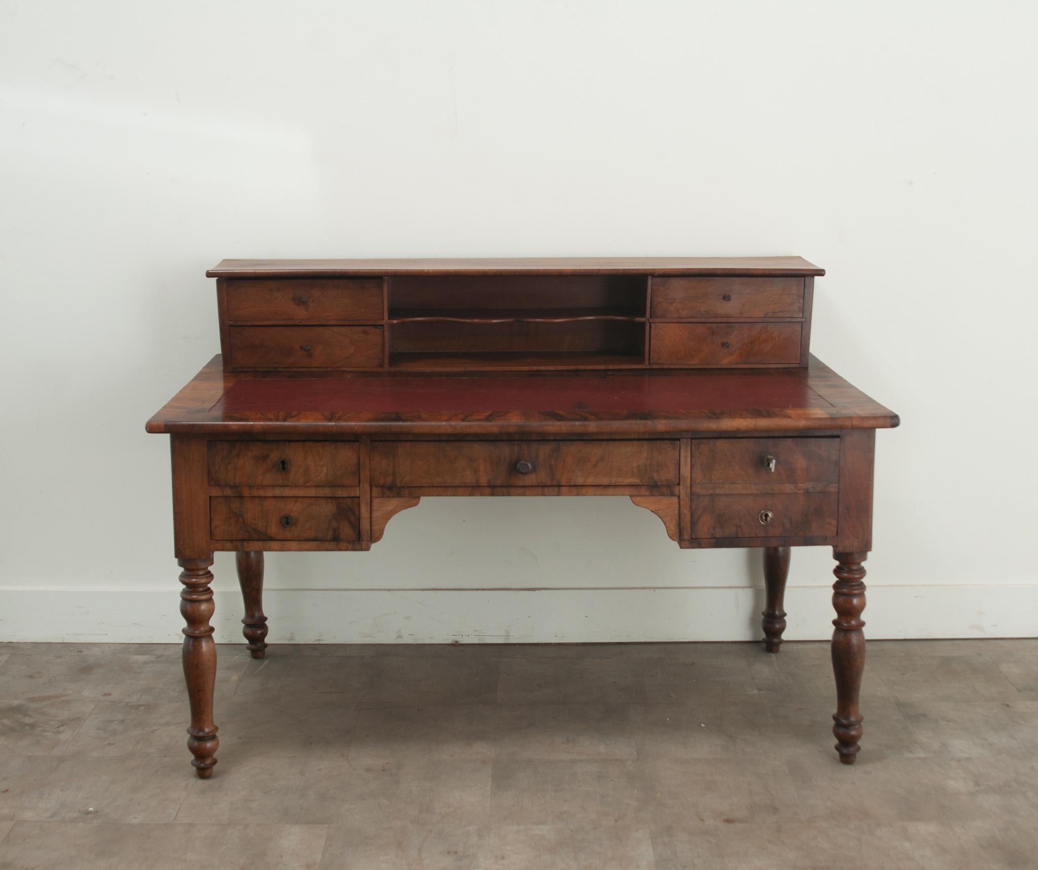 A French writing desk made of rosewood and mahogany. This desk has an upper console containing four drawers and a center open cavity with a scalloped shelf. The writing surface has an inset leather top and has a pull out slide on its right side for