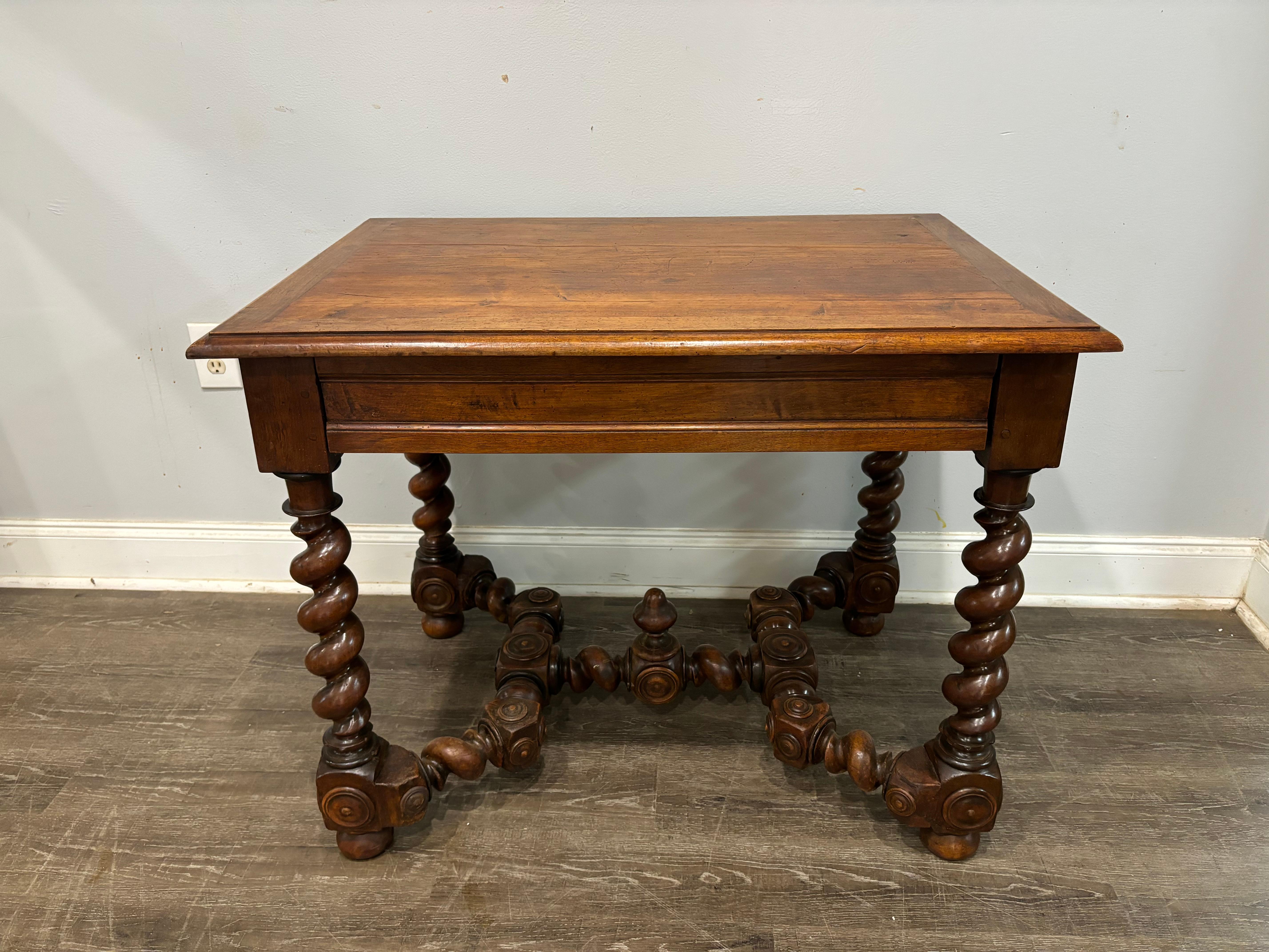 Cette table à écrire de style Louis XIII est fabriquée en noyer et possède un tiroir caché dans la jupe. 