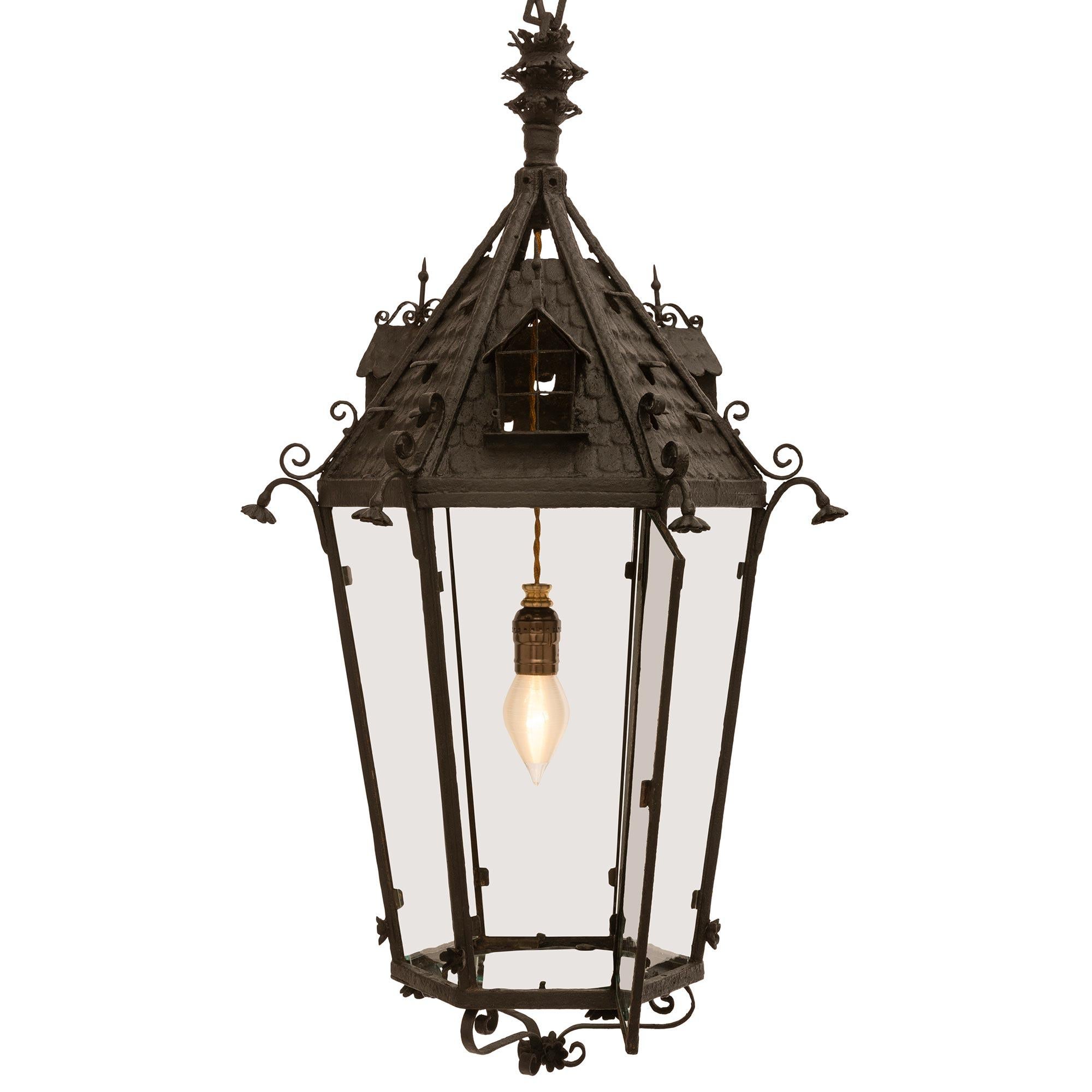 A very decorative and unique French 19th century Wrought Iron lantern. The bottom of the hexagon shaped lantern is elegantly decorated by elongated 'S' scrolls leading to the bottom of the tapered hexagon frame of the lantern with flower like