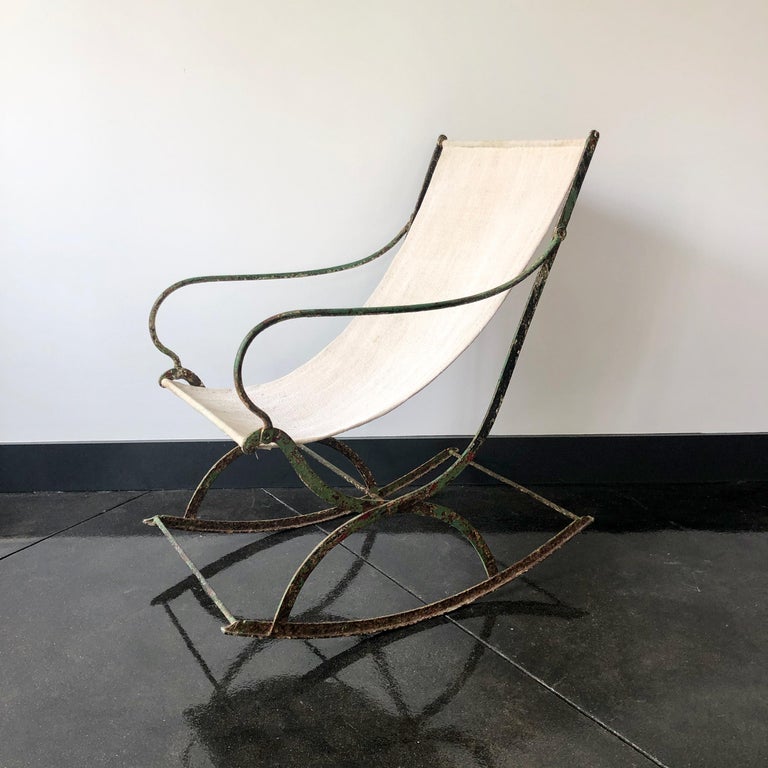 Rare 19th century French wrought iron rocking chair with most of its original green paint with patient rust. Upholstered in natural colored antique linen.