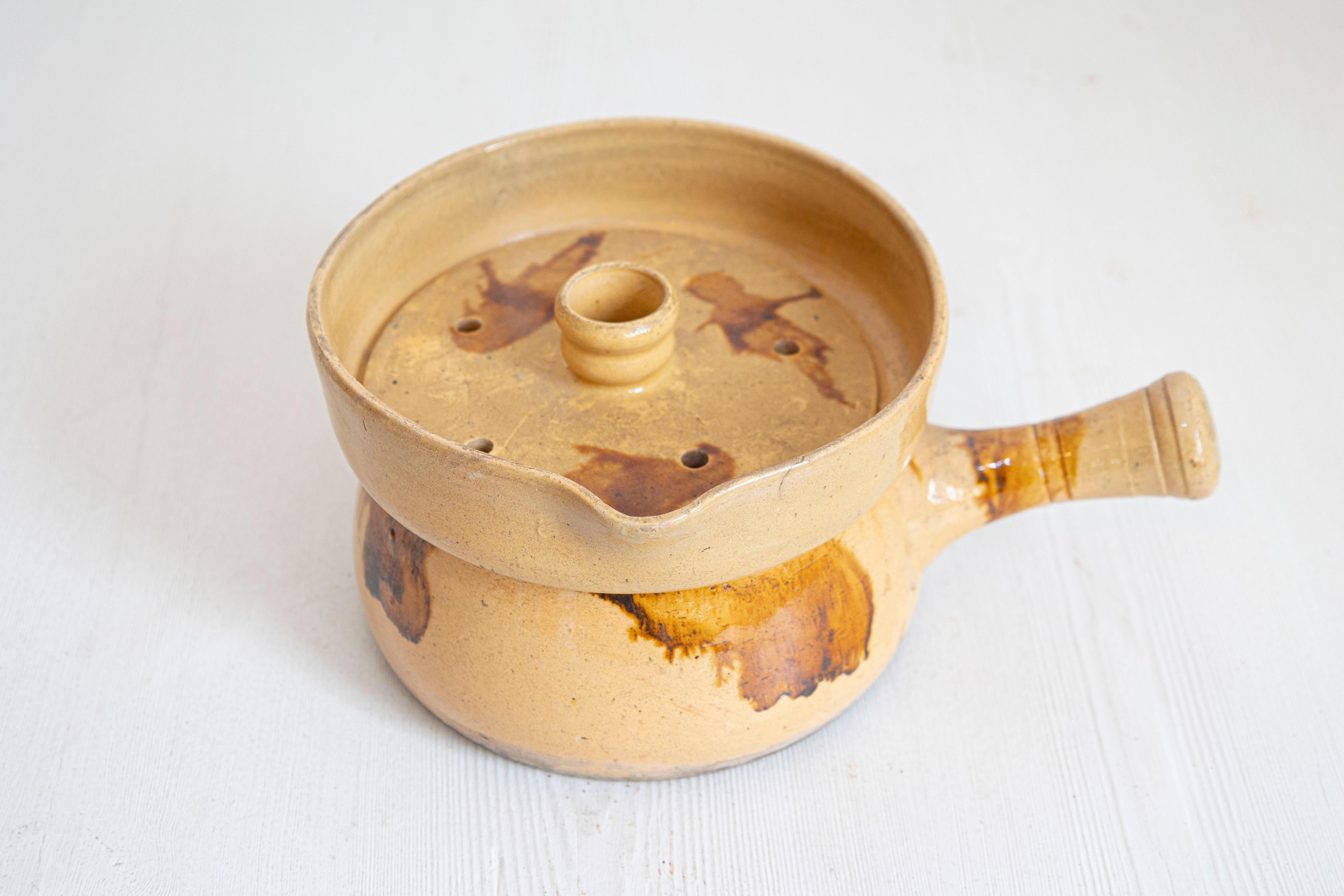 Vaporera de cerámica francesa del siglo XIX, con tapa y detalles de óxido. Creada en Francia durante el siglo XIX, esta vaporera de cerámica presenta un cuerpo circular esmaltado en amarillo adornado con detalles en tono óxido. Con tapa y asa recta,