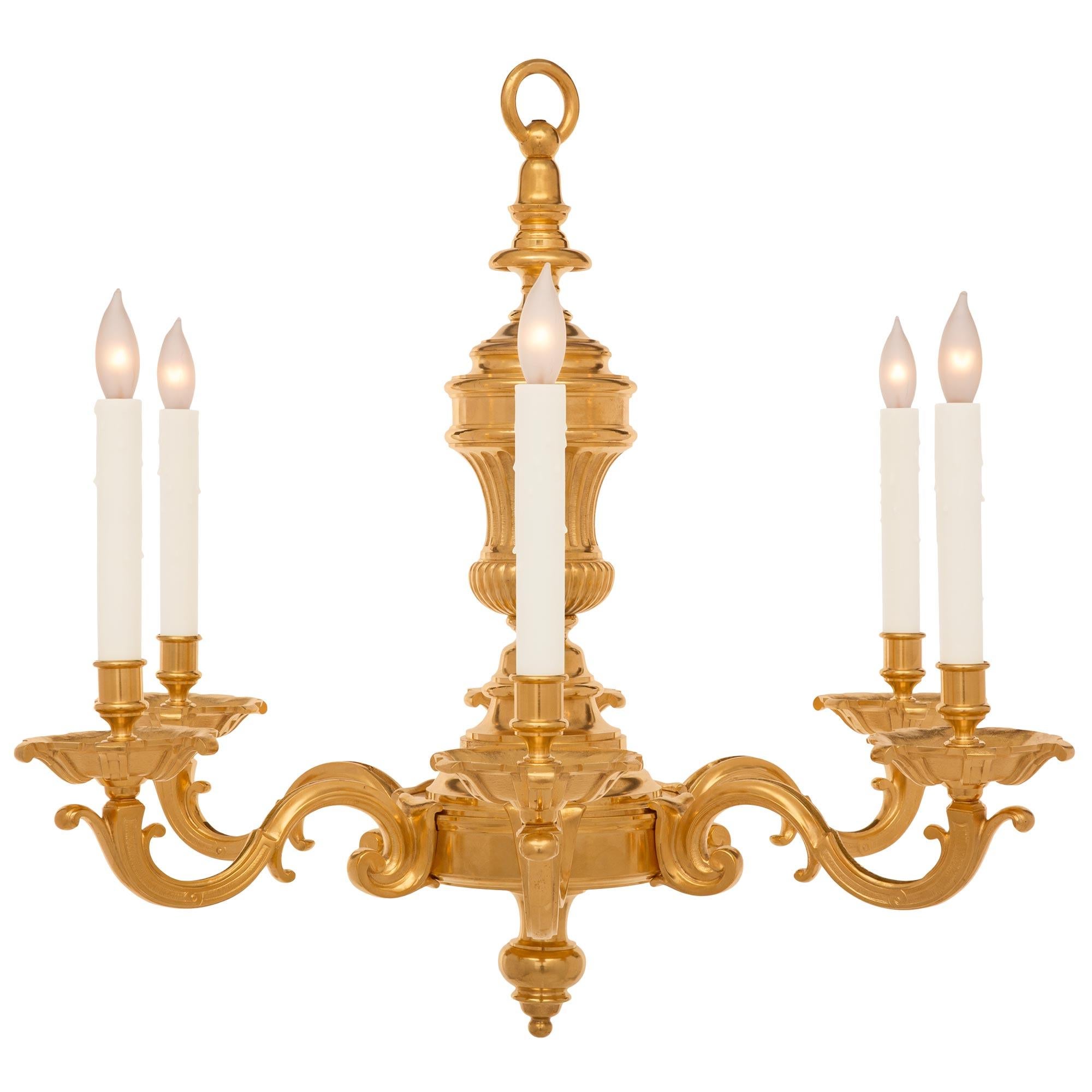 A most elegant French 19th Louis XVI st. ormolu chandelier. The six arm chandelier is centered by a lovely mottled topie shaped bottom finial. The body displays a decorative stepped and mottled design from where the elegantly scrolled arms branch