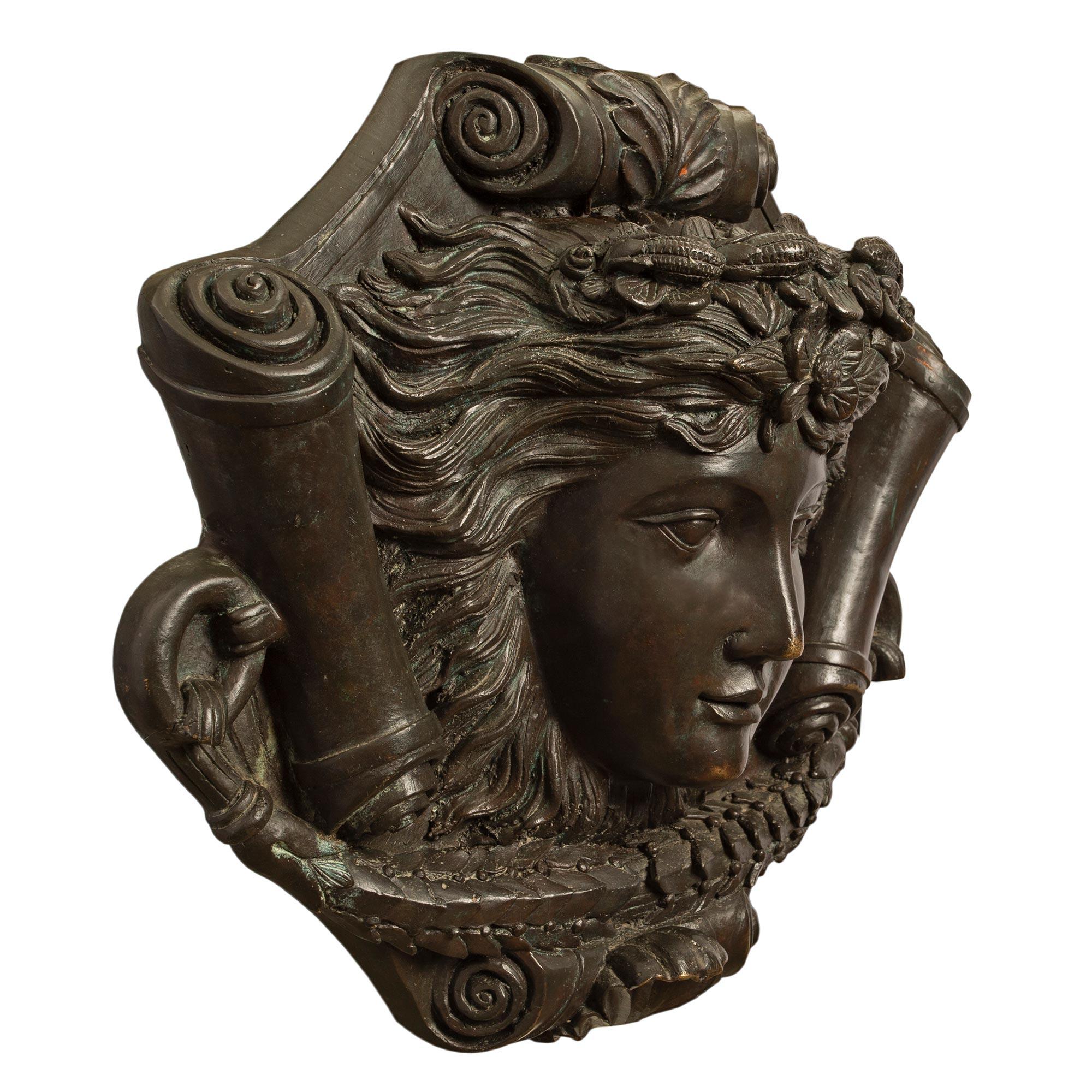 A fine quality and handsome French 19th Louis XVI st. patinated bronze decorative wall plaque. The center of the plaque has a richly chased female mask with flowers in her hair. Her eyes are open and she is flanked by rolled scrolls. At each side is
