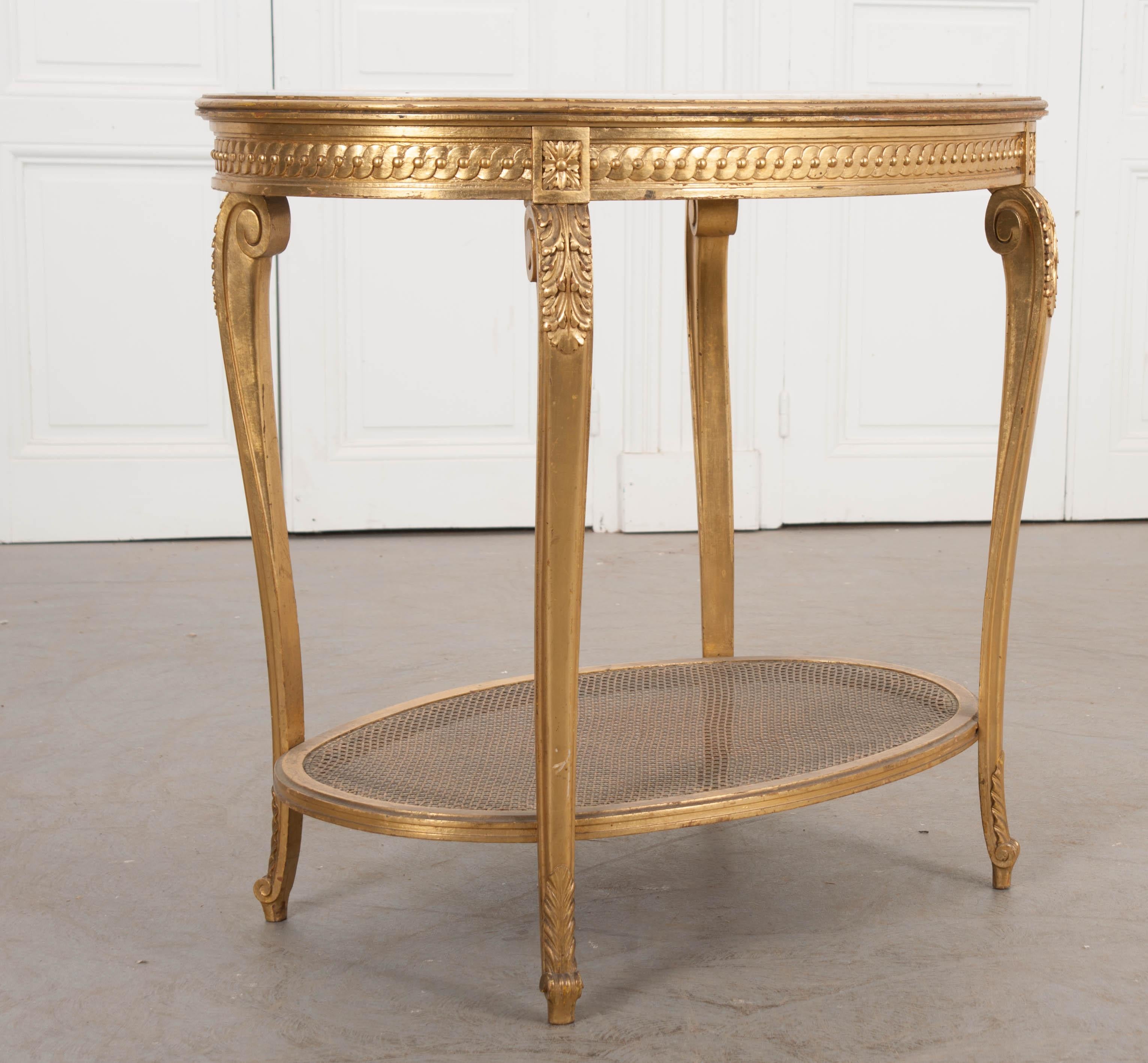 Cette gracieuse table d'appoint ovale en bois doré, vers 1880, est originaire de France et présente un plateau en marbre blanc délicatement veiné de gris, sur un tablier minutieusement sculpté, avec quatre pieds en cabriole évasés et des pieds