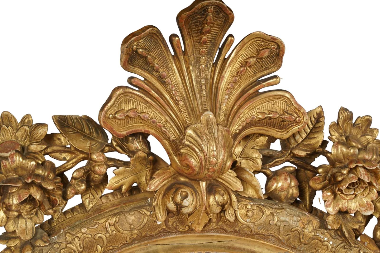 Miroir en bois doré du 19ème siècle avec un motif floral partant du centre du miroir vers le haut. Bon état d'usage. Usure mineure due à l'âge et à l'utilisation. 56h x 41 w
