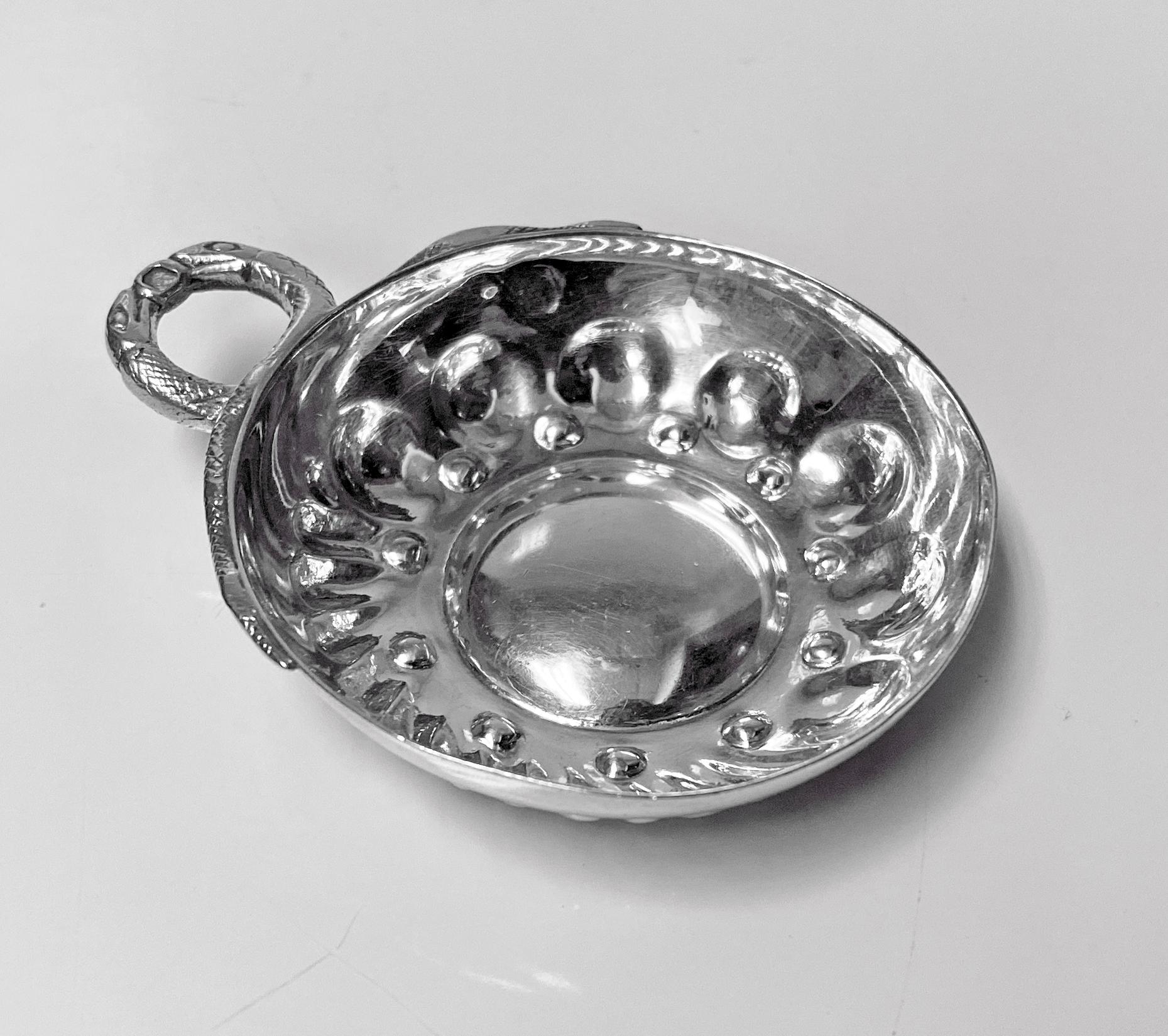 French 1st std .950 silver wine taster Tastevin, 20th century, maker's mark in lozenge. The Tastevin of usual form, the lower part of bowl with a surround of concave and swirl lobate style decoration, double entwined serpent handle, also marked with