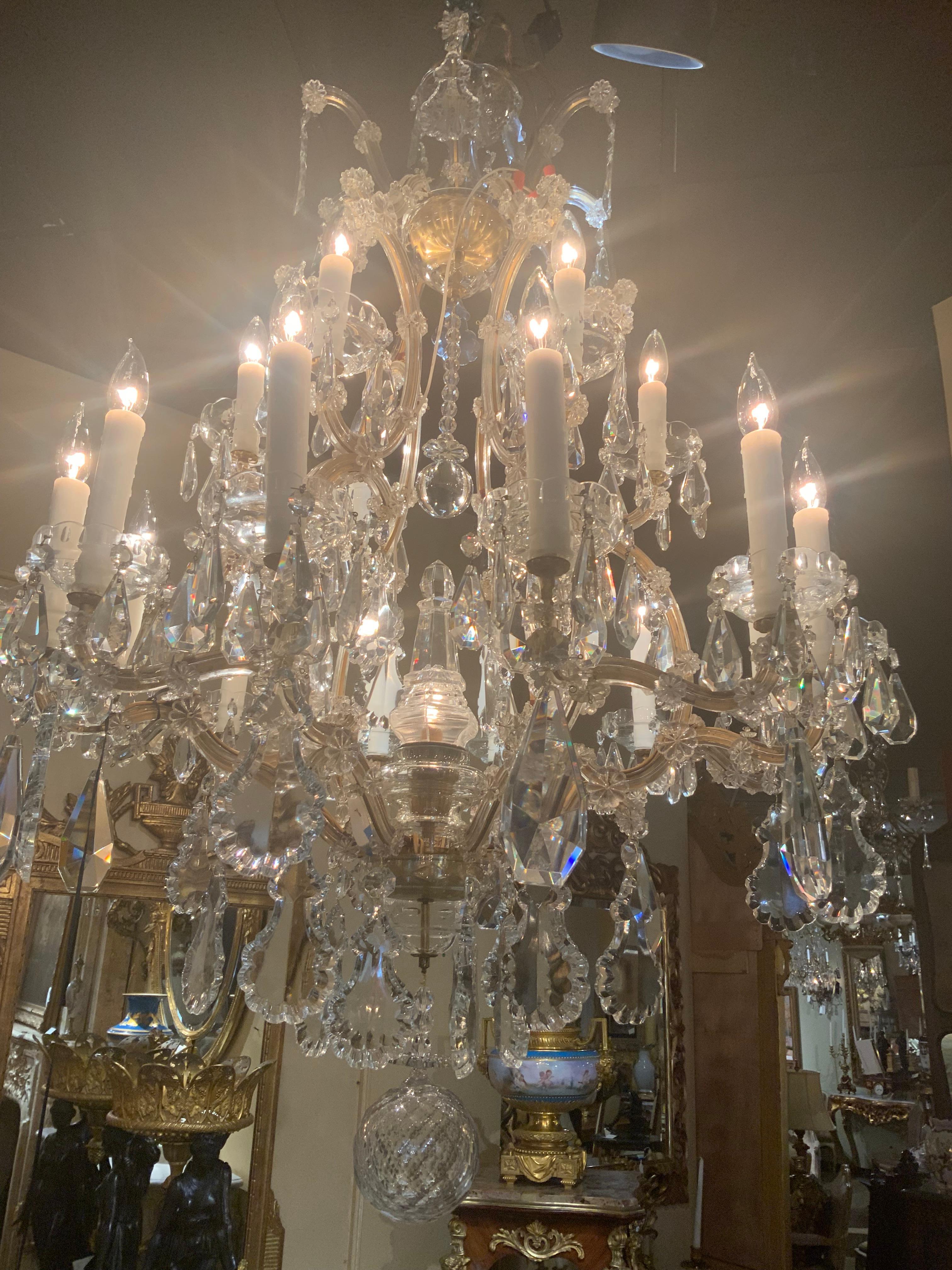 Grande lampadario di cristallo a venti luci con eleganti volute
Braccia.  Anche la grande guglia che si trova al centro è dotata di una luce.
Termina con una grande e bellissima palla. Il cablaggio è buono e
Non ha pezzi rotti, scheggiati o