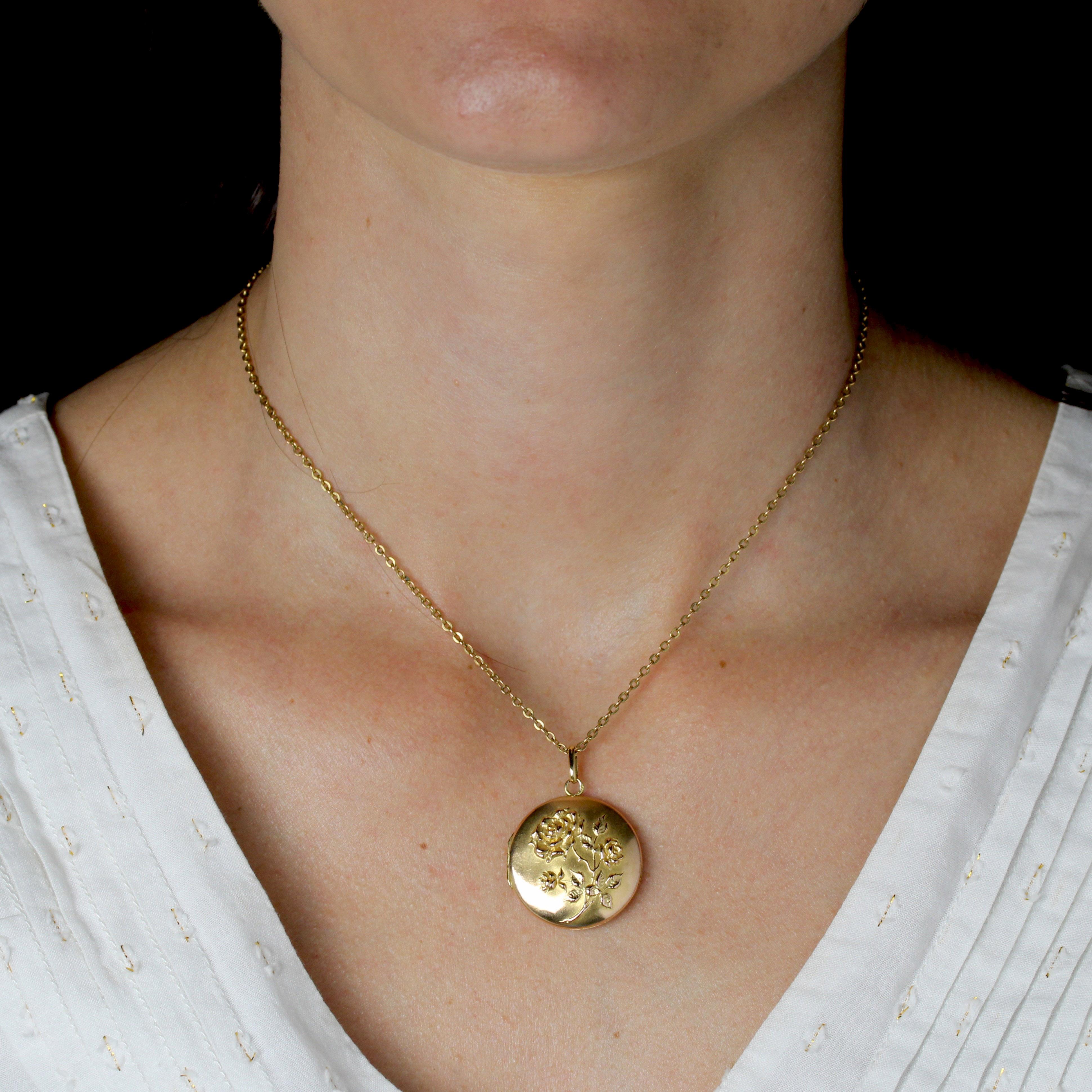 Pendentif en or rose 18 carats, poinçon tête d'aigle.
Pendentif féminin ancien de forme ronde, gravé sur le devant de motifs représentant un bouquet de roses et leur feuillage. Le dos est lisse. Il s'ouvre à l'aide d'une charnière sur le côté et