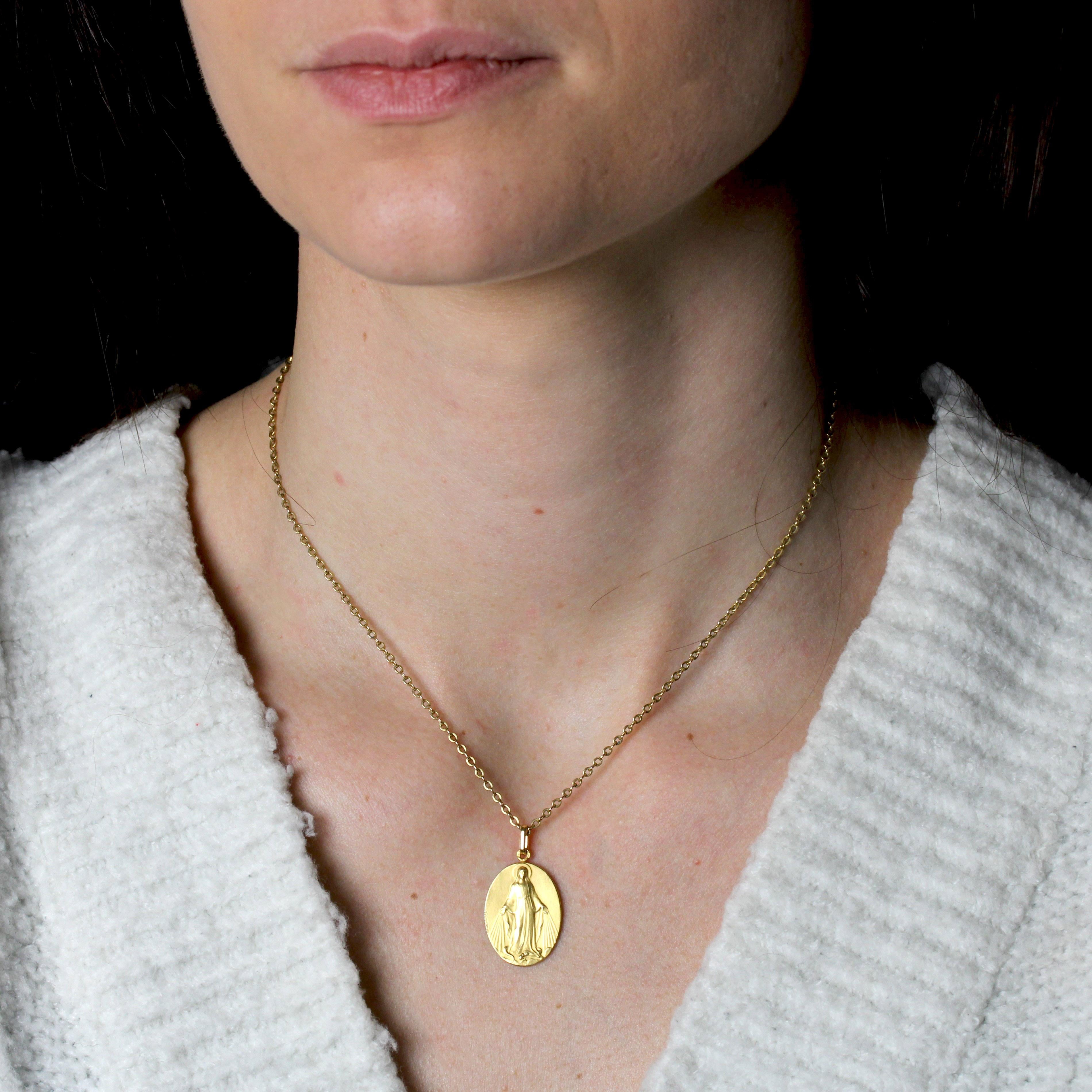 Medal in 18 karat yellow gold, eagle head hallmark.
An oval-shaped medal in matt gold, it depicts the Virgin Mary crushing a snake. On the back are other symbols, such as the “M” of Mary topped by a cross and surrounded by 12 stars. They are