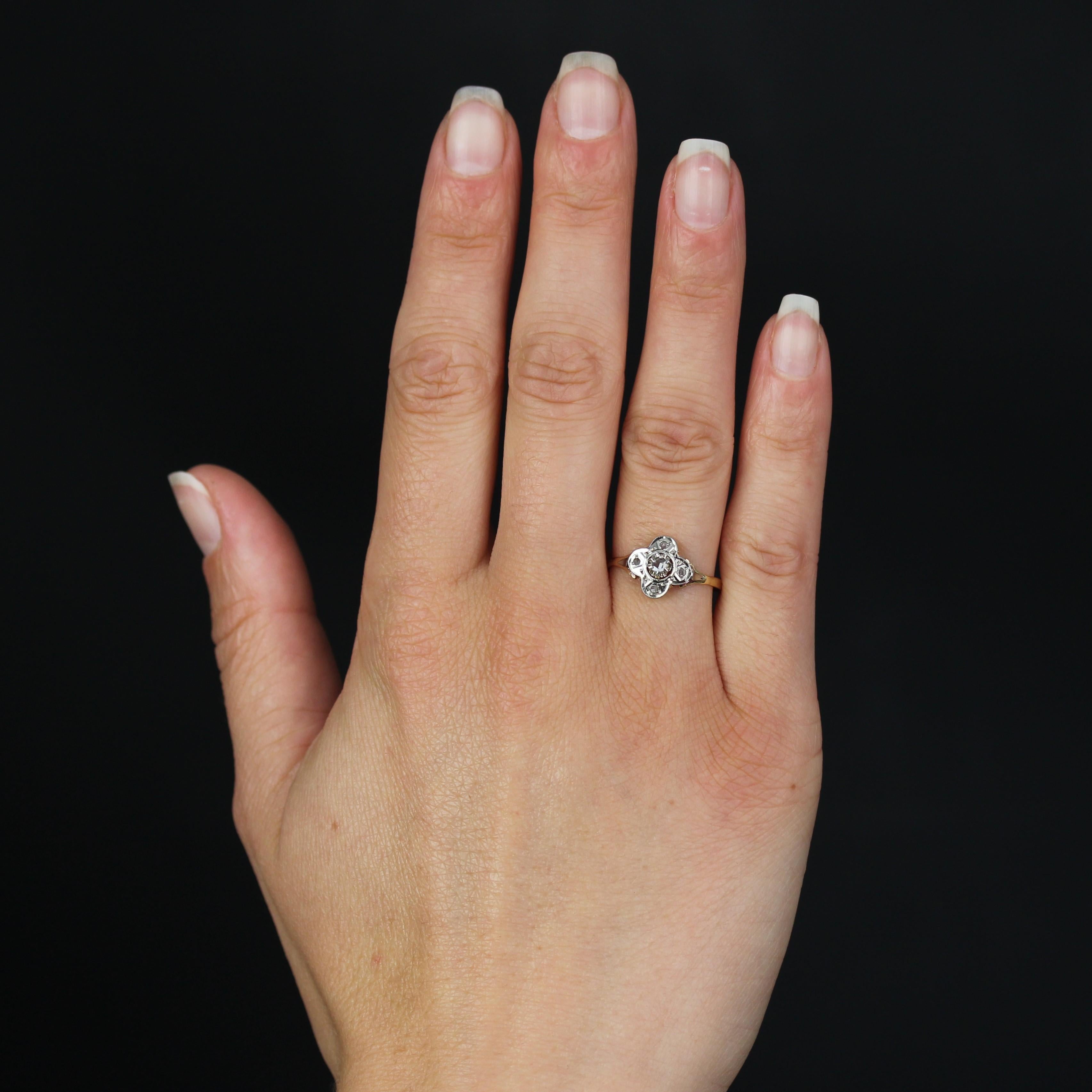 Ring in 18 karat yellow and white gold, eagle head hallmark.
This charming antique ring forms a cloverleaf with rose-cut diamonds at each end and a larger rose-cut diamond in the claw-set center. The openwork basket and band are in yellow