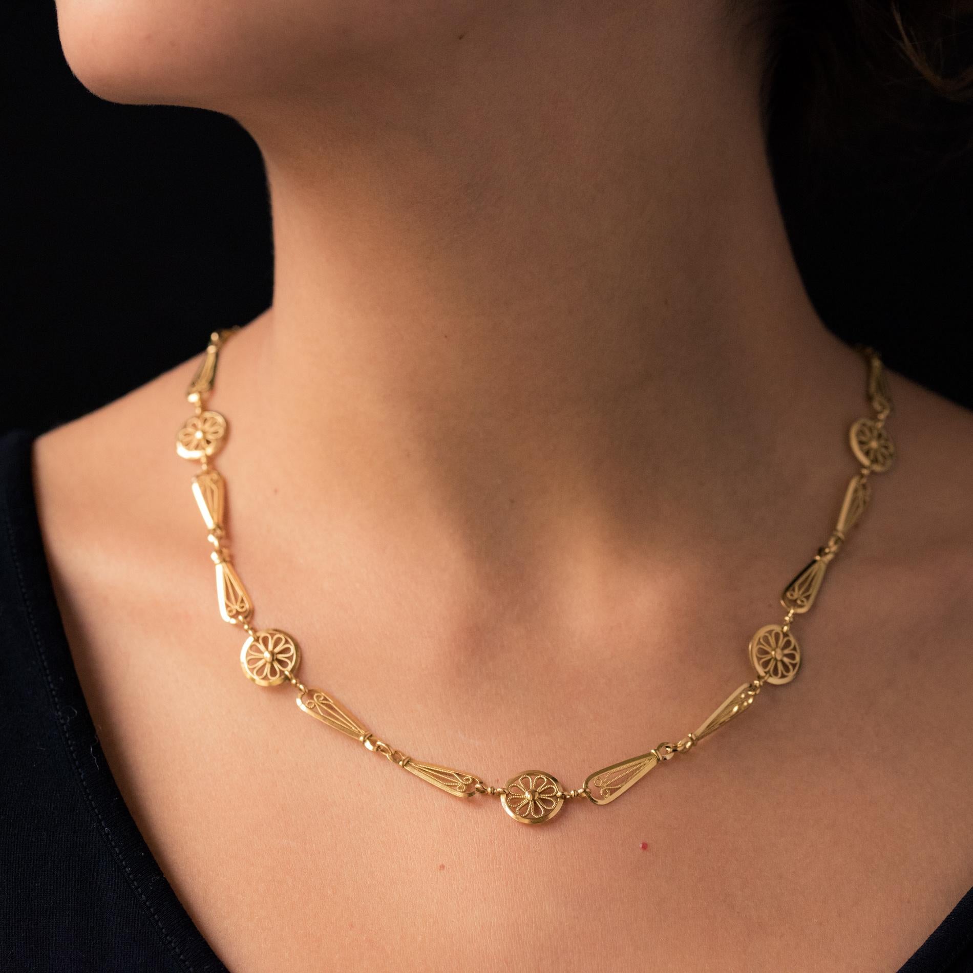Chain in 18 karat yellow gold, rhinoceros' head and eagle's head hallmarks.
This necklace is made up of openwork discs of filigree flowers, each retained by two pear motifs with the same decor. The clip is a spring ring.
Length: 49 cm, width: 1.2