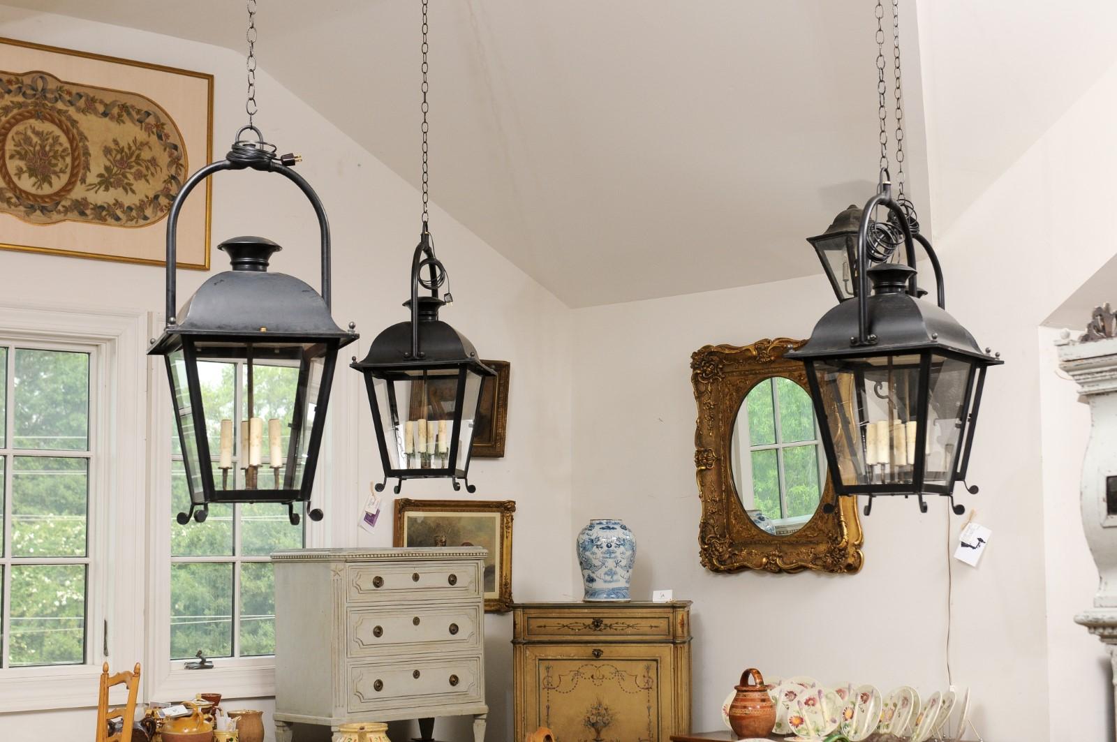 French black painted iron four-light lanterns from the 20th century, with four glass panels, domed tops and scrolling feet, priced and sold individually $3,500 each. Created in France during the 20th century, each of these four iron lanterns