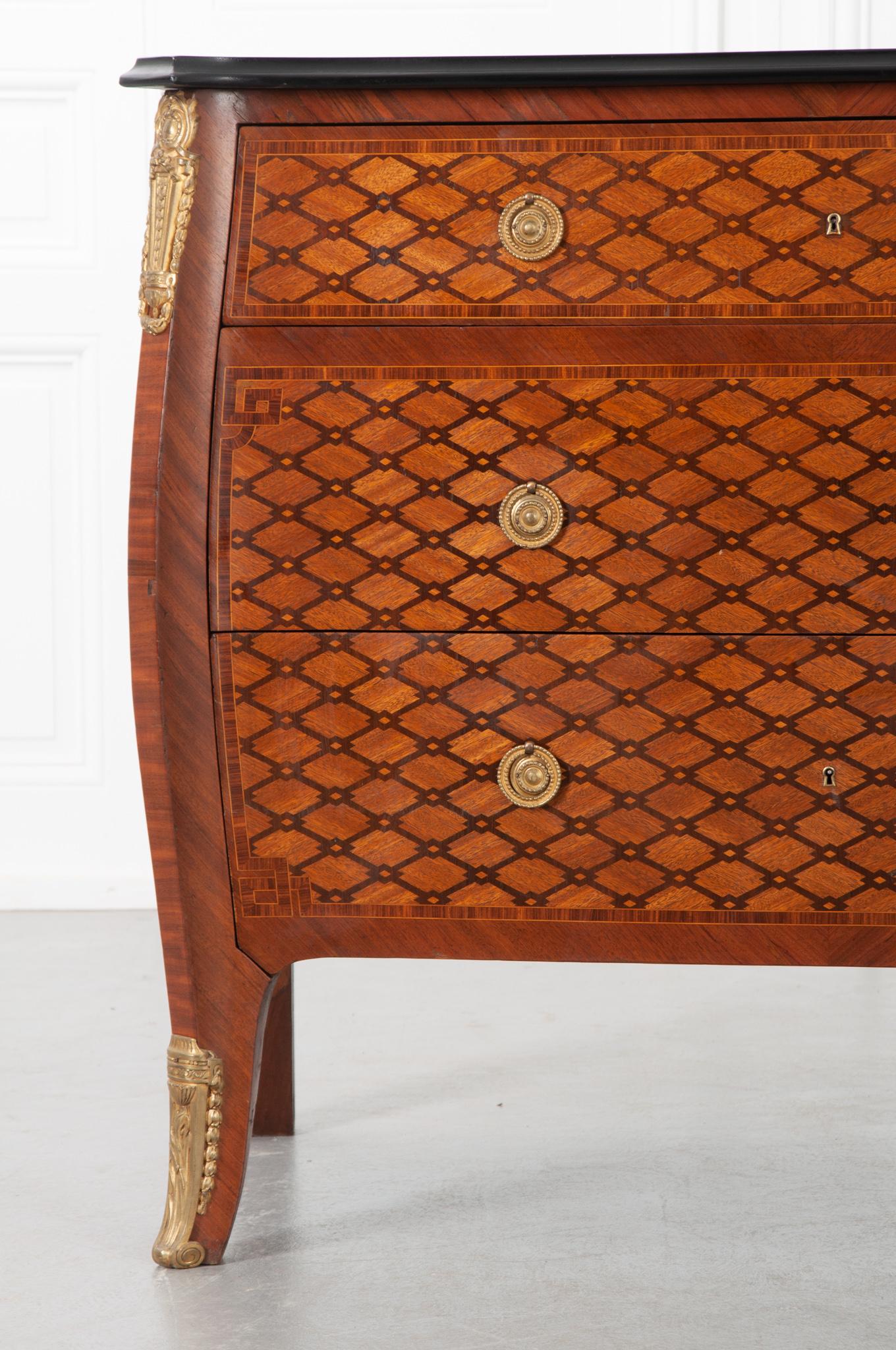 This striking commode was made in the 1900’s with newer technology that allowed for such an impressive display of marquetry. The drawer fronts are curved and follow the bombay shape with ring brass pulls. You’ll find impressive casts of ormulo on