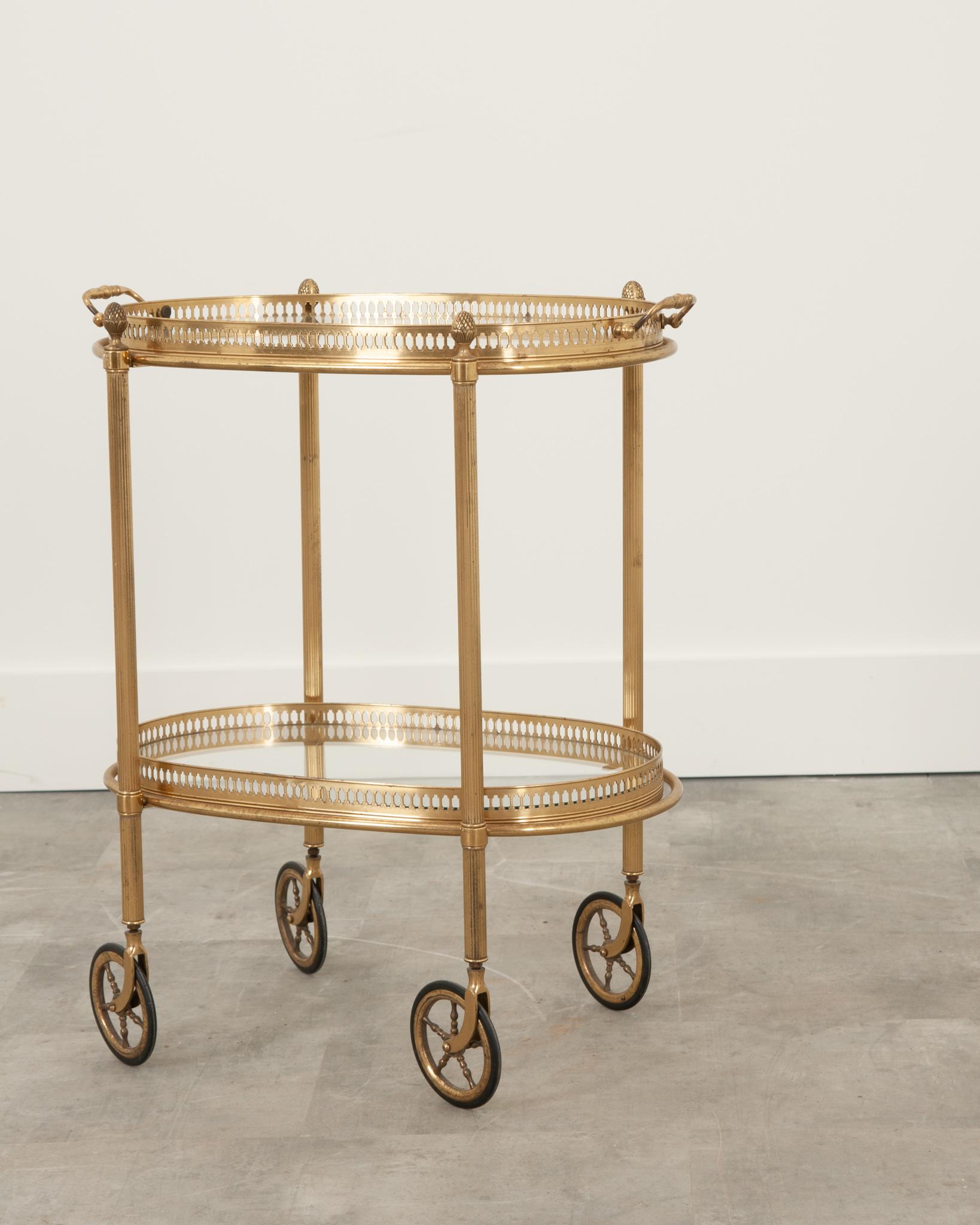 This darling French vintage bar cart is sure to impress guests at your next gathering. Complete with two removable glass trays surrounded by a pierced brass gallery- only the top tray features handles. Ribbed legs each feature a decorative artichoke