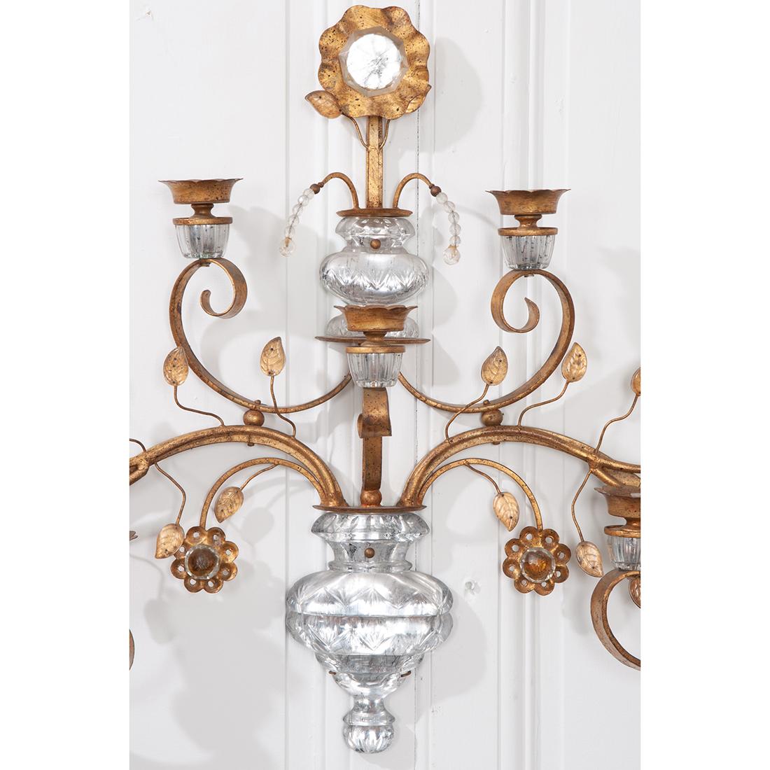 This beautiful French 20th century sconce features a brass scroll design with crystal accents. The sconce has floral and foliate details with each leaf and flower having crystal embellishments. There are seven candle holders. Reproduction. 
 