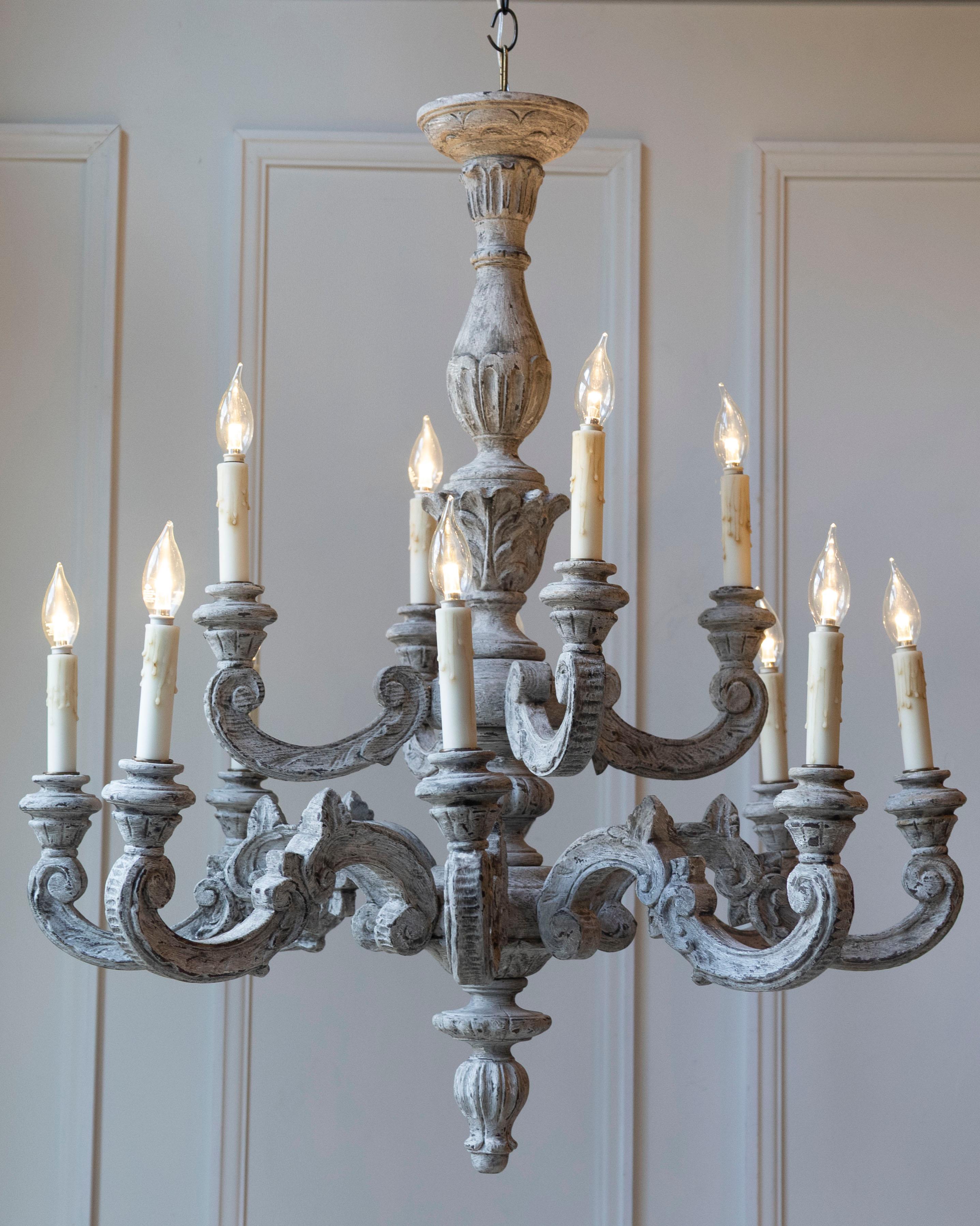 Questo imponente lampadario francese del XX secolo è un'opera in legno finemente intagliata, che si distingue per la sua grande scala e i suoi dettagli scultorei. Progettato con dodici bracci che scorrono con grazia, ognuno dei quali termina con