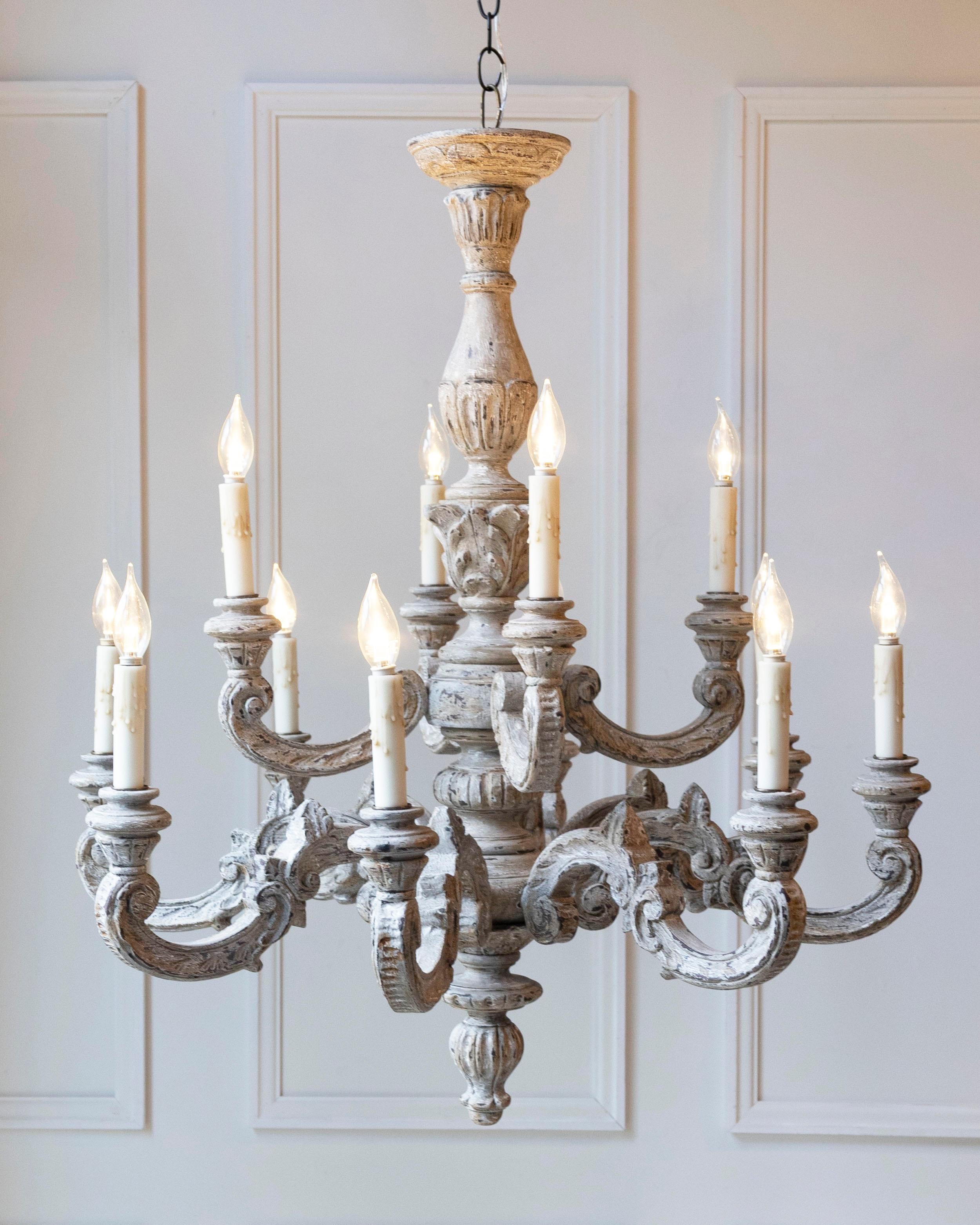 Questo imponente lampadario francese del XX secolo è un'opera in legno finemente intagliata, che si distingue per la sua grande scala e i suoi dettagli scultorei. Progettato con dodici bracci che scorrono con grazia, ognuno dei quali termina con