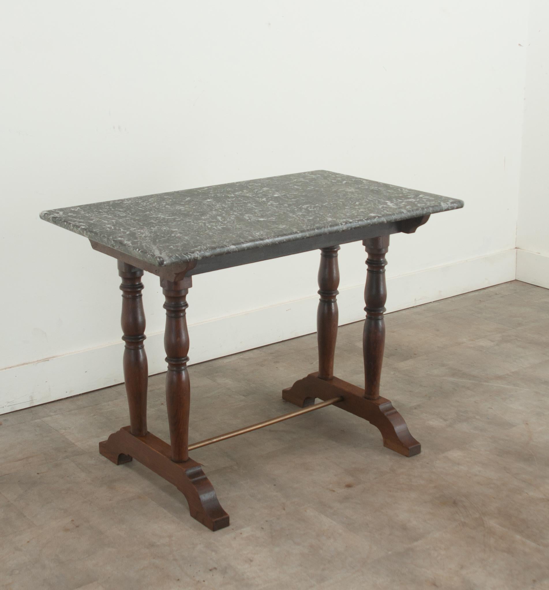 An early 20th Century oak, marble, and brass bistro table. The original St.Anne marble top is beautiful and durable, raised over four turned oak legs over bracket feet and a brass stretcher. Cleaned and polished with a French paste wax this antique