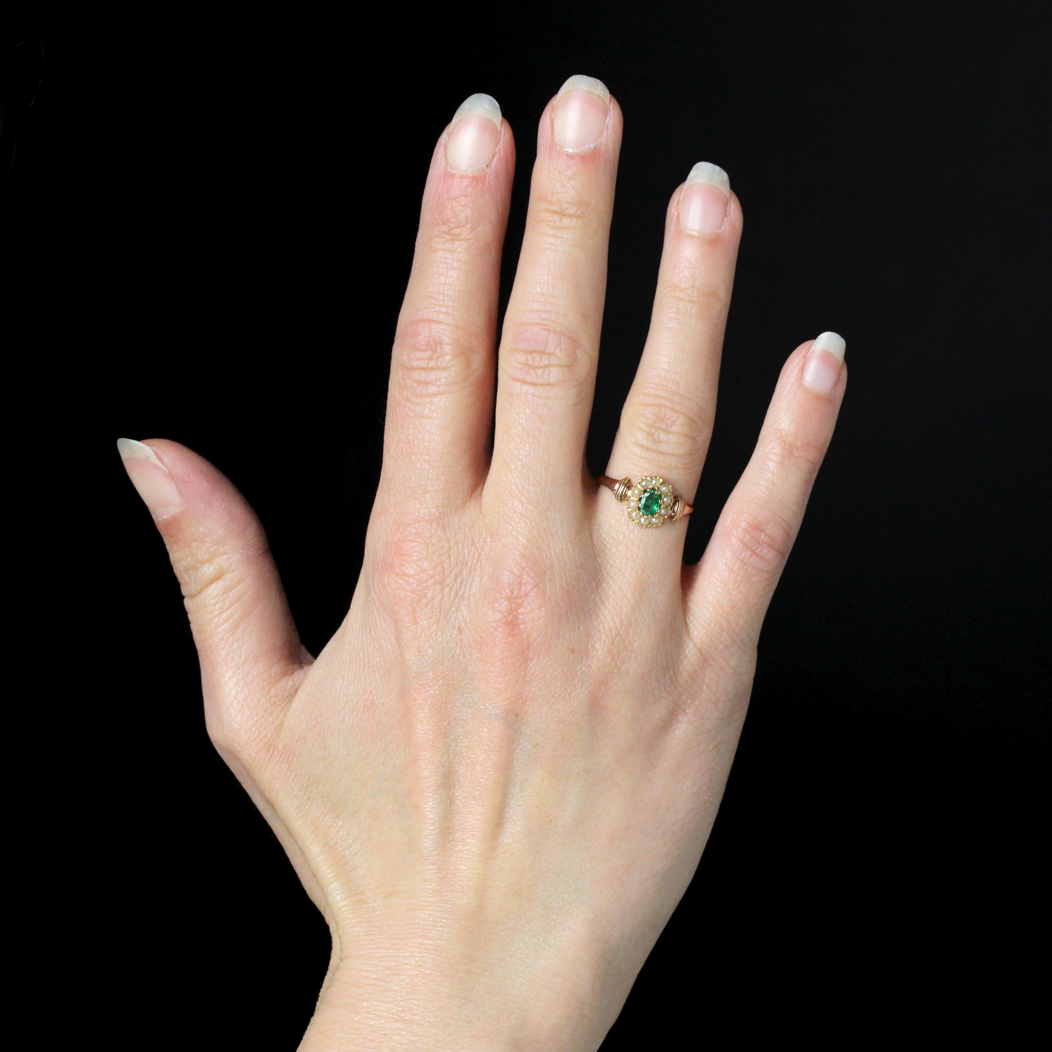 Ring in 18 karat rose gold, eagle head hallmark.
This charming antique ring features an oval setting with a claw-retained emerald in the center. Ten fine half-pearls surround the emerald, and the opening of the ring is adorned with a chased,