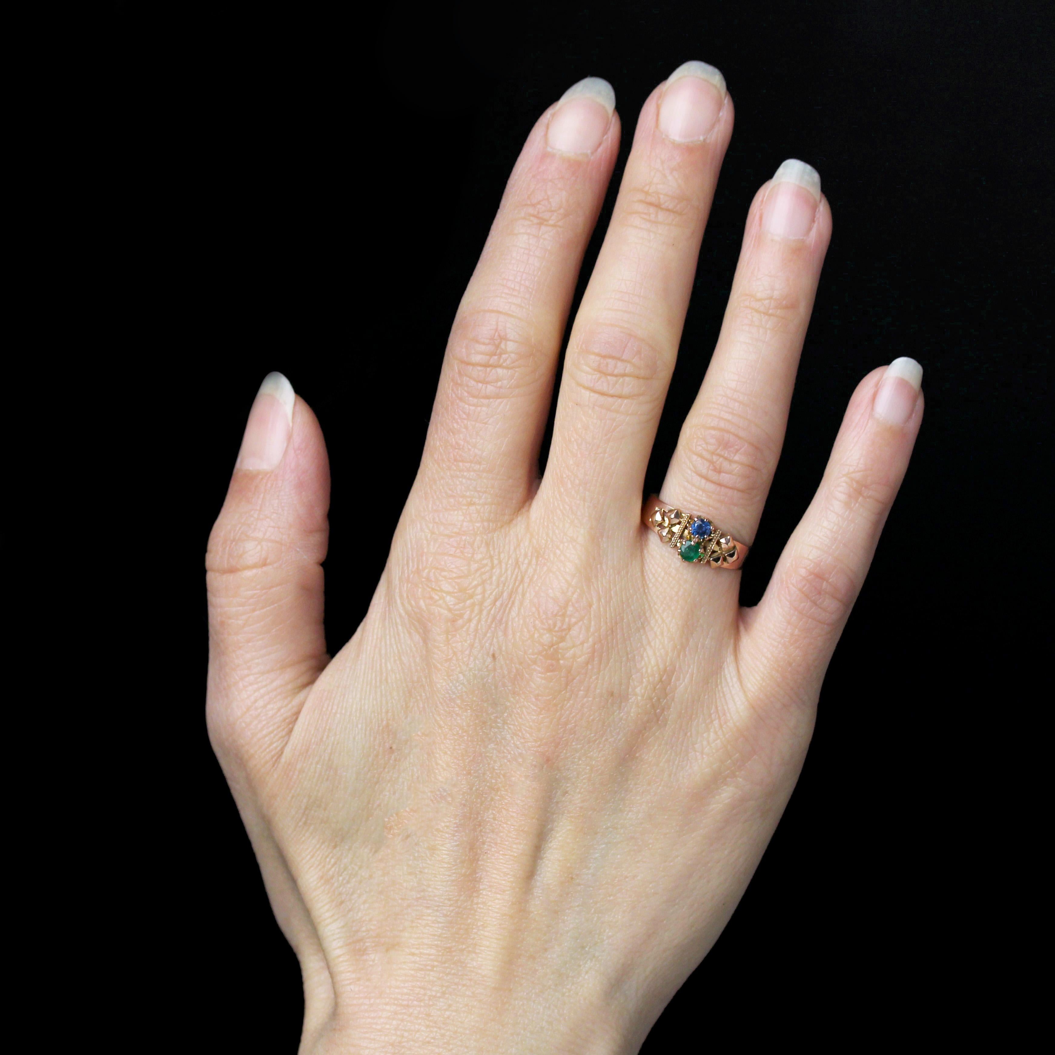 Bague en or rose 18 carats, poinçon tête d'aigle.
Charmante bague ancienne du début du XXe siècle, son large anneau est orné sur le dessus d'une émeraude ronde et d'un saphir rond, tous sertis en griffes. Les pierres précieuses sont soutenues de