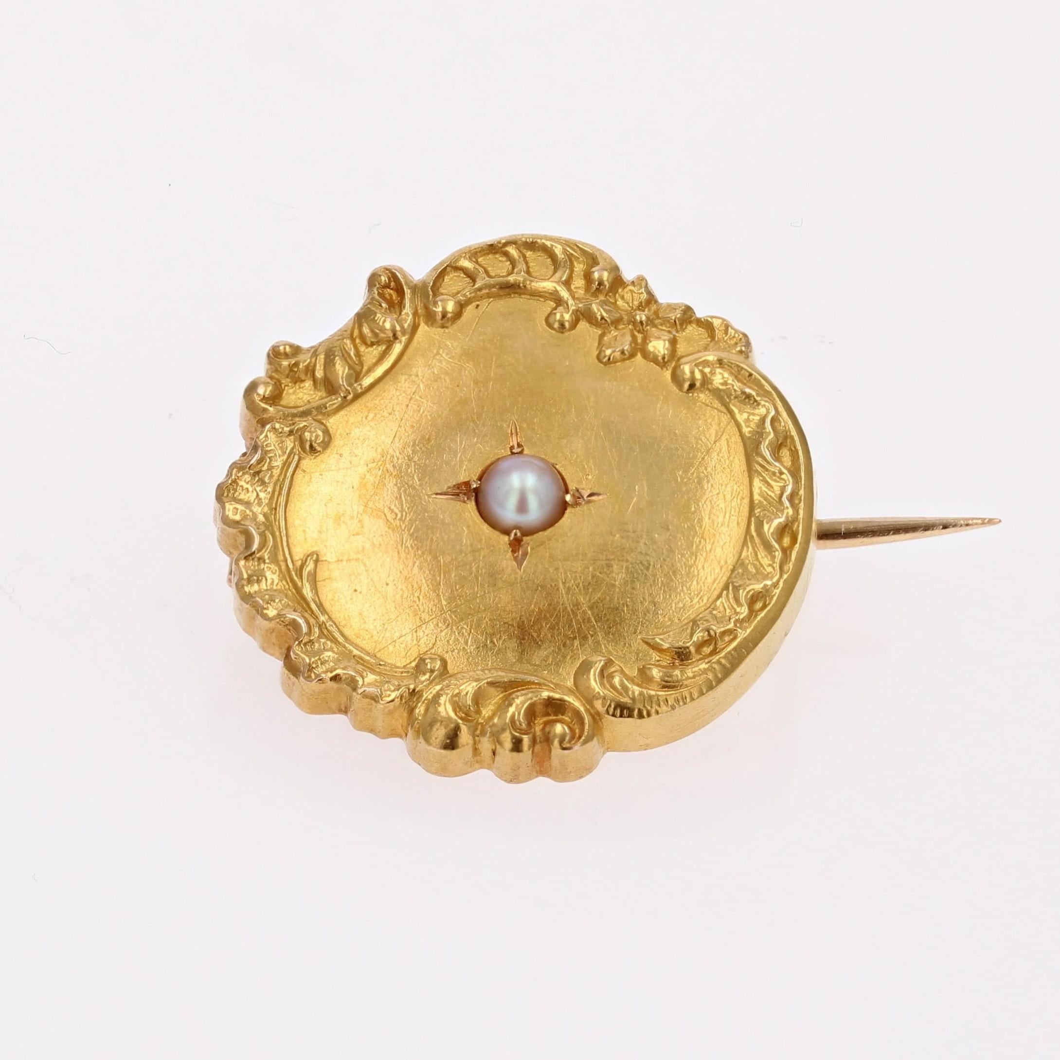 Brooch in 18 karat yellow gold, eagle head hallmark.
This round collar brooch in yellow gold is bordered by a floral and arabesque design and features a fine half-pearl in the center. The fastening system is a safety pin.
Pearl diameter : 2/2.5 mm