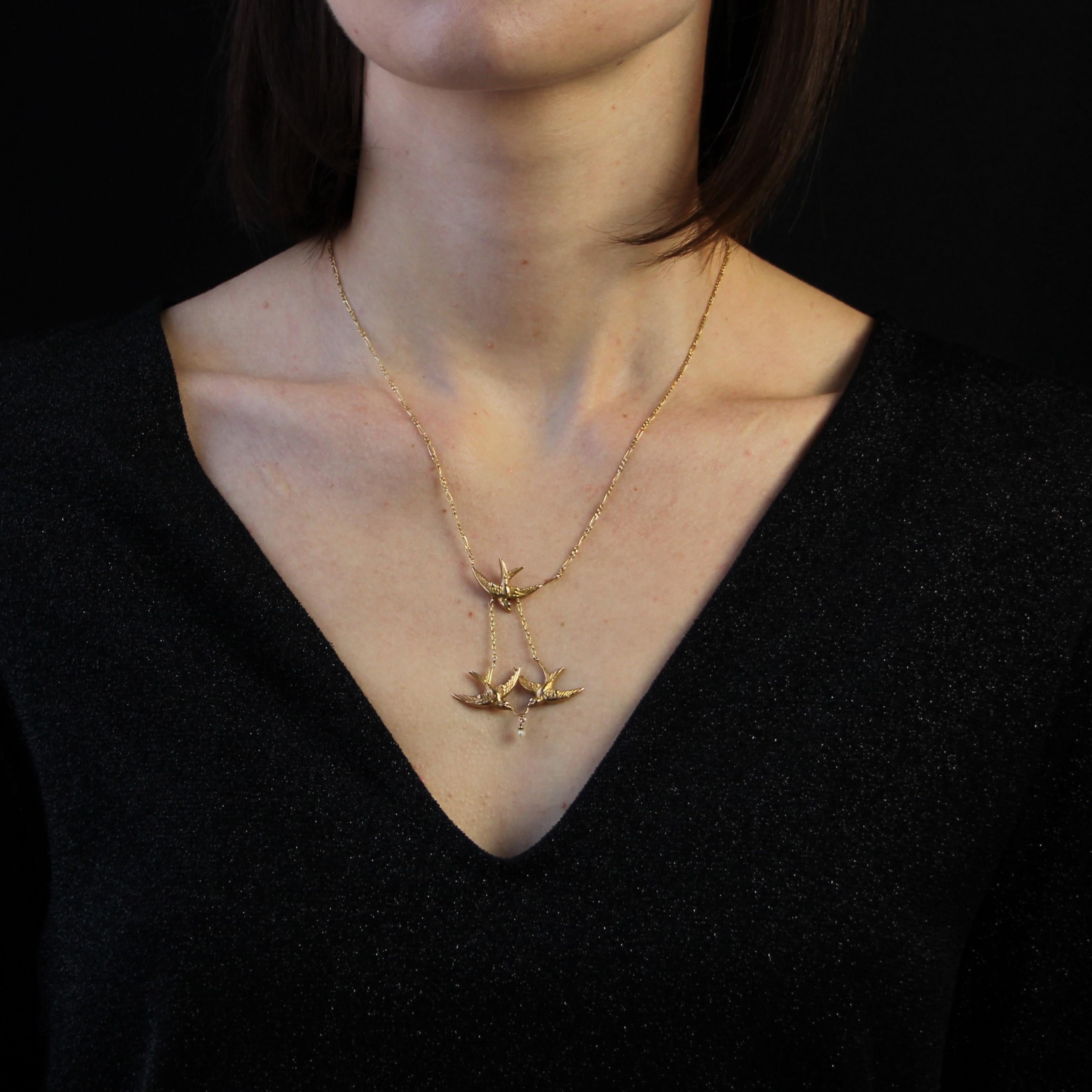 Necklace in 18 karat yellow gold, eagle head hallmark.
This delicate antique necklace is made of fine alternating gourmette mesh holding a motif of 3 swallows on the front, 2 of which are tassels holding a small baroque pearl in their beak. The
