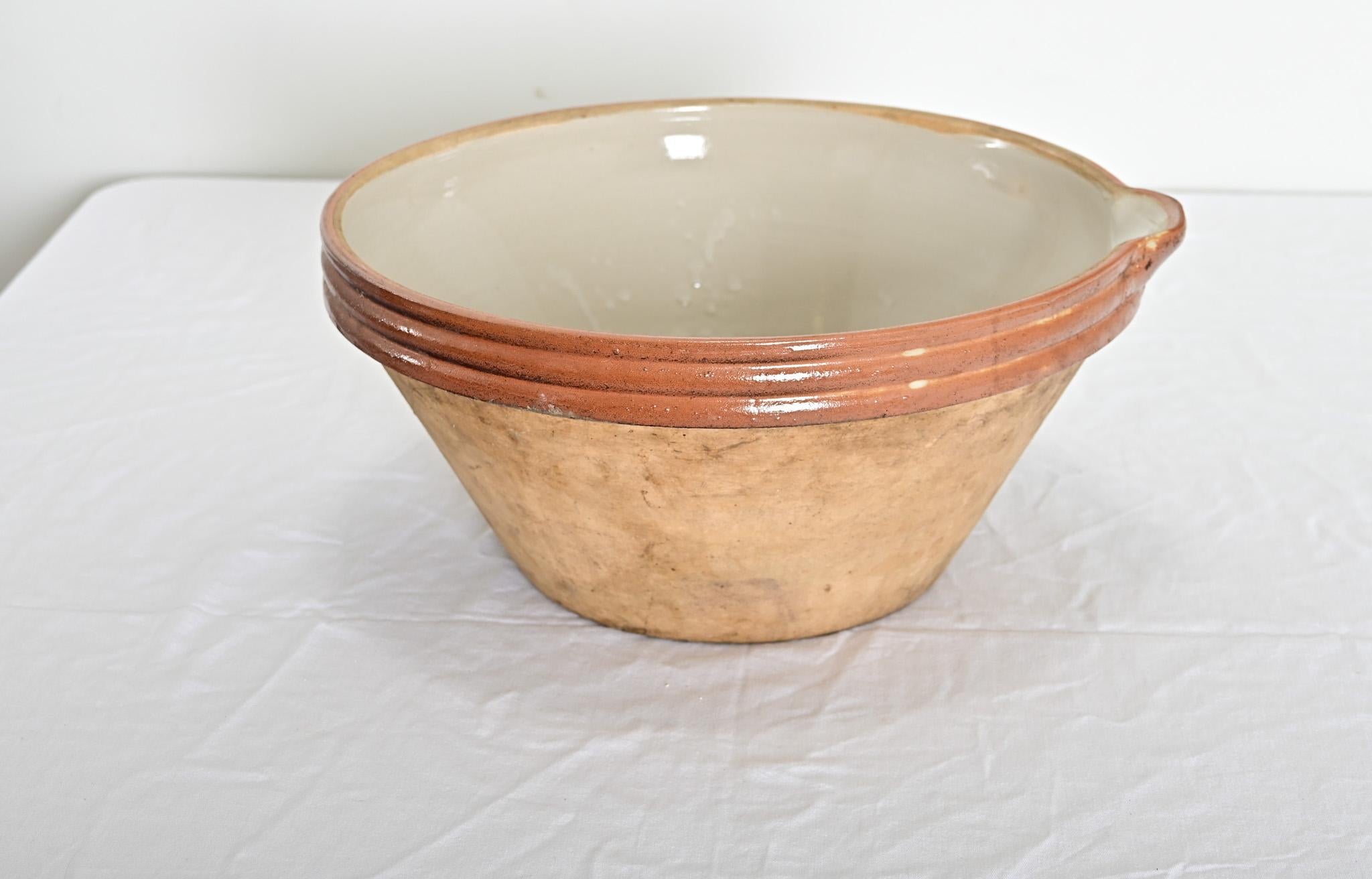 A lovely glazed terra cotta cream bowl from early to mid-20th century France. This earthen bowl–also known as a pancheon–was used to stand milk while the cream separates, then the cream is then poured off the top bythe small spout found on the pot’s