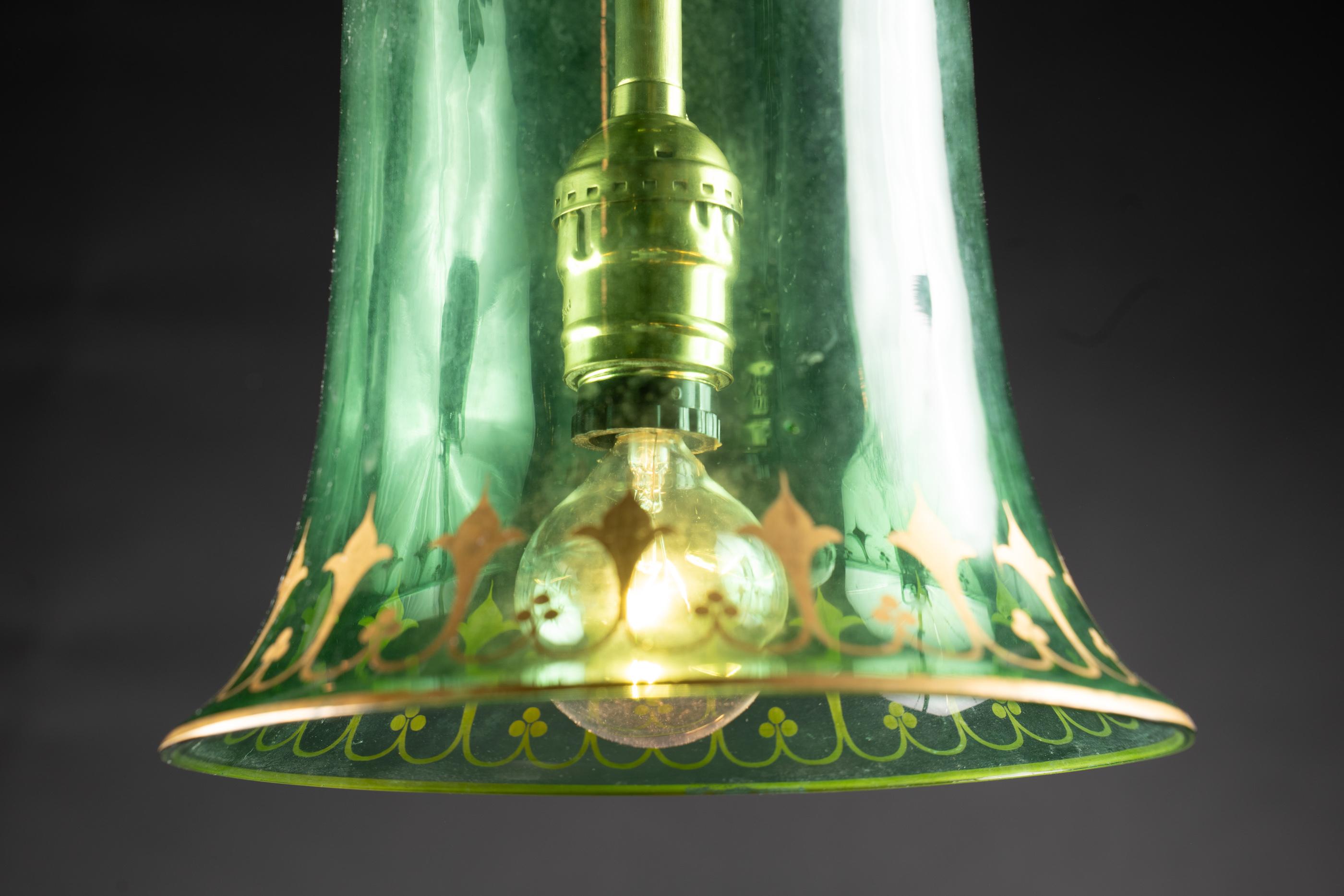 Globe suspendu en forme de cloche, en verre teinté vert, décoré d'une fine gravure à l'or fin.


