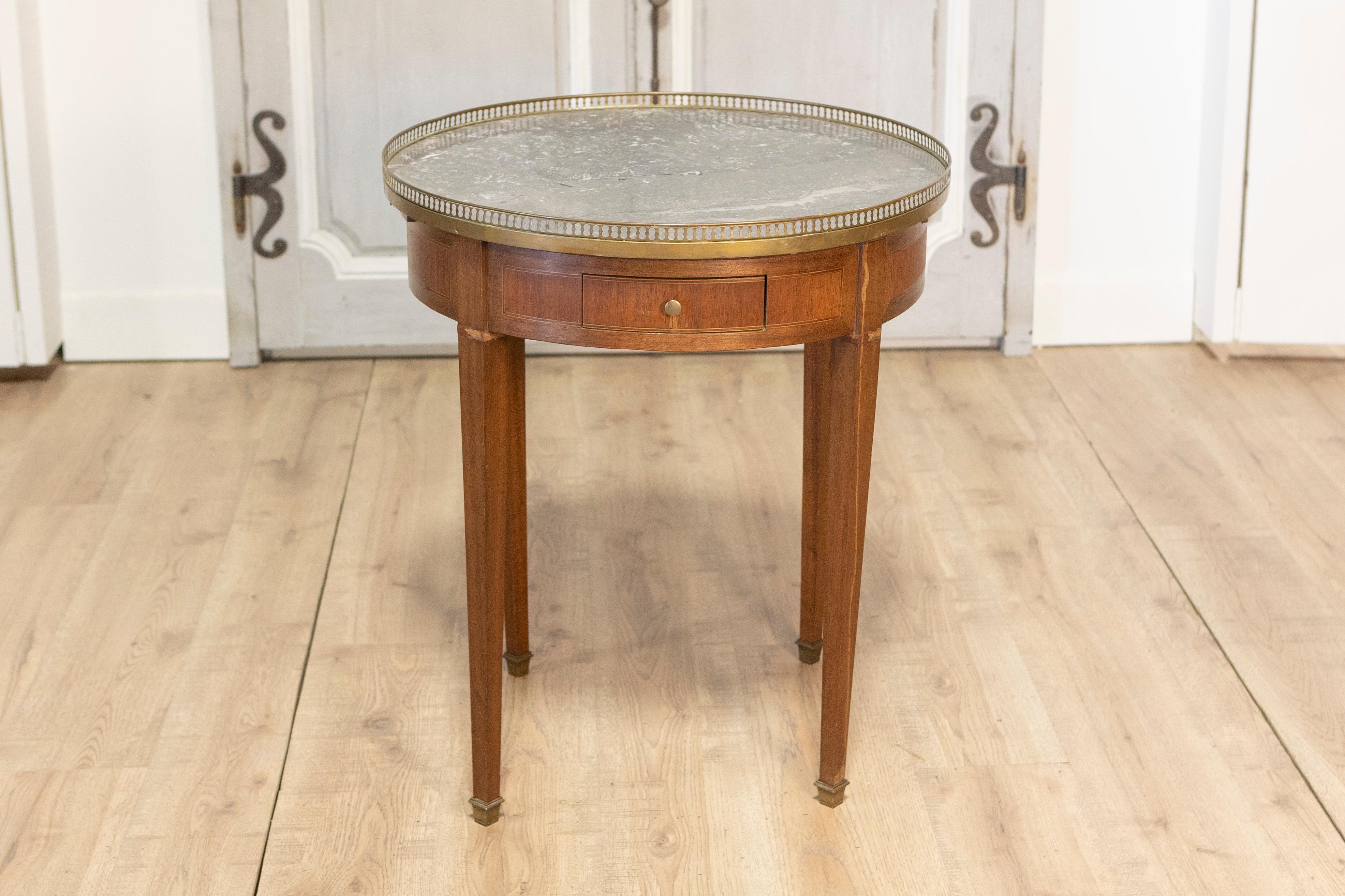 Questo elegante tavolo bouillotte francese, realizzato all'inizio del XX secolo, incarna la raffinatezza senza tempo dello stile Luigi XVI. Caratterizzato da un piano rotondo in marmo con morbide venature, il tavolo è incorniciato da una delicata