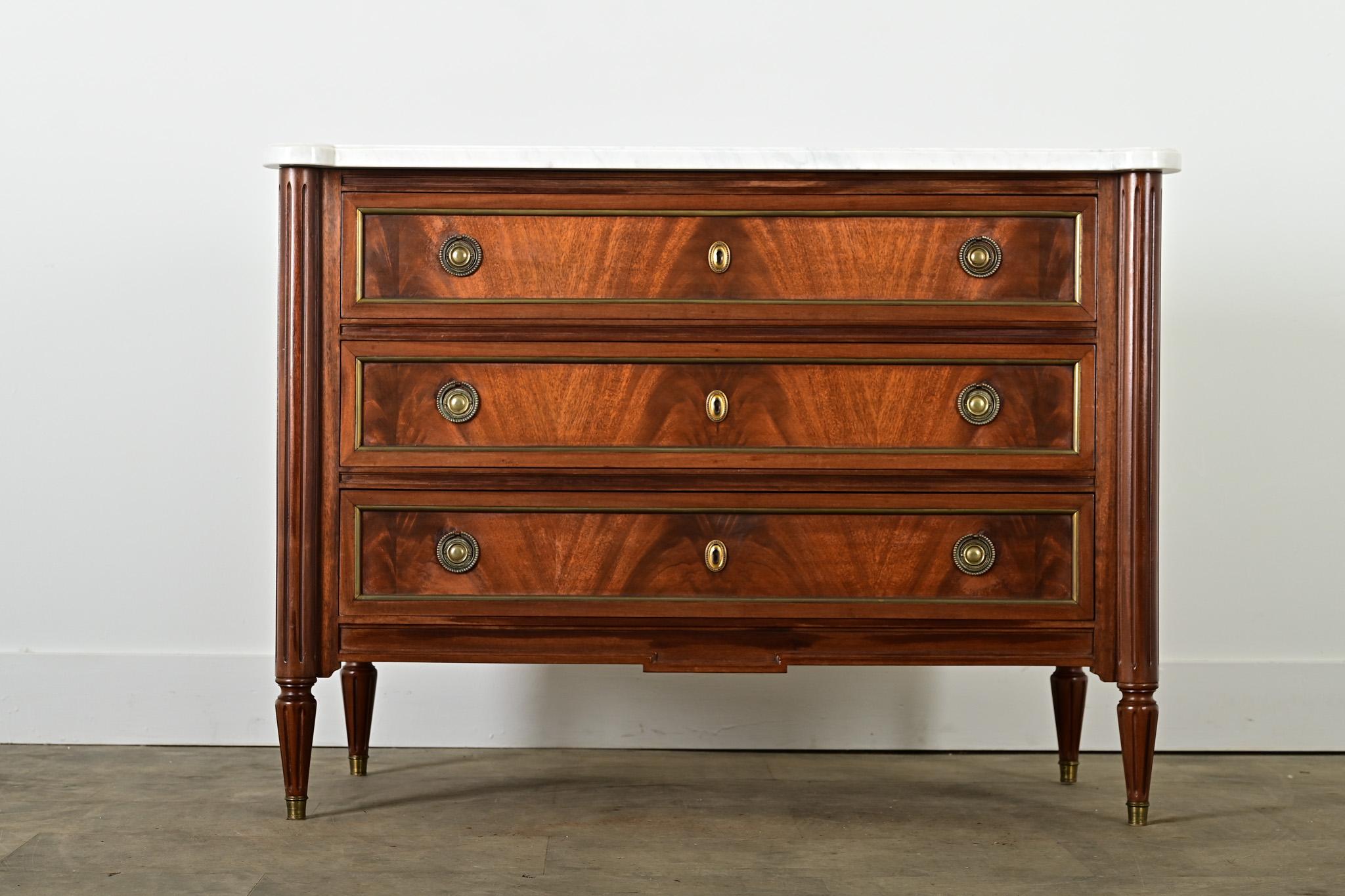 A glorious 20th century vintage reproduction Louis XVI-style commode from France, true to the spirit of an antique original with a marble top on a mahogany & beech wood case of three drawers. The white stone exhibits fine veining and a polished