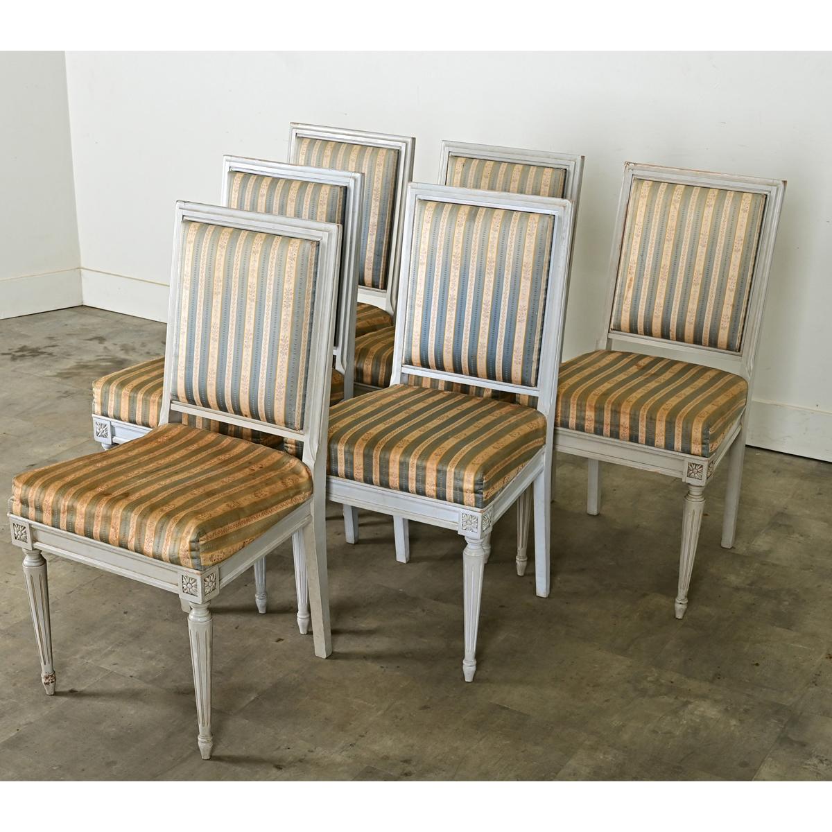 A lovely set of six Louis XVI style painted and upholstered armless dining chairs, circa 1930. Their clean silhouettes of straight lines and squared backs is softened by the French gray painted wood frames showing light patina. Striped