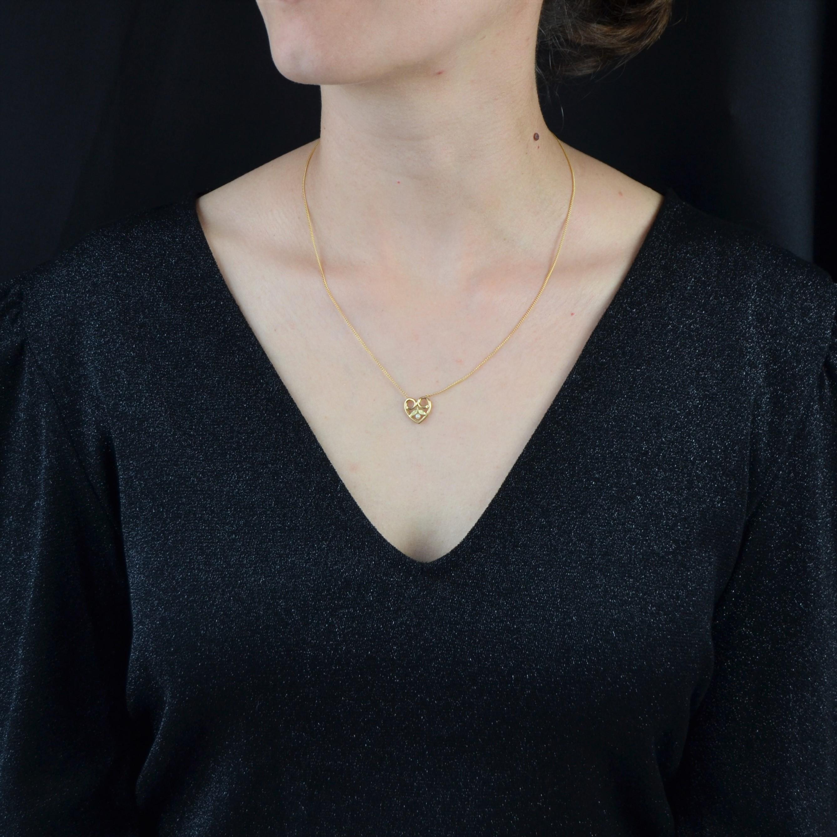 Necklace in 18 karat yellow gold, eagle head hallmark.
Antique jewel of charm, this necklace is made of a thin mesh holding, on the front, a heart-shaped pattern, openwork and decorated with a half pearl, and small gold leaves. The clasp is a spring