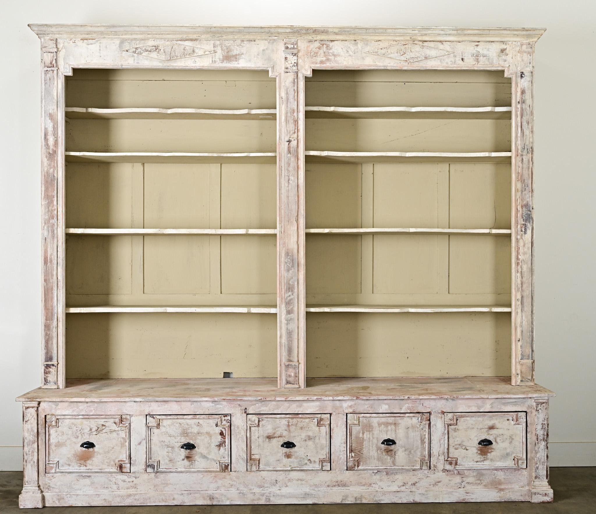 Encantadora librería francesa antigua del siglo XX, pintada y patinada, que incorpora elementos anteriores de estilo Directoire del siglo XIX para darle un aspecto único e histórico bajo el pigmento blanco desgastado. En este ejemplo -siguiendo las