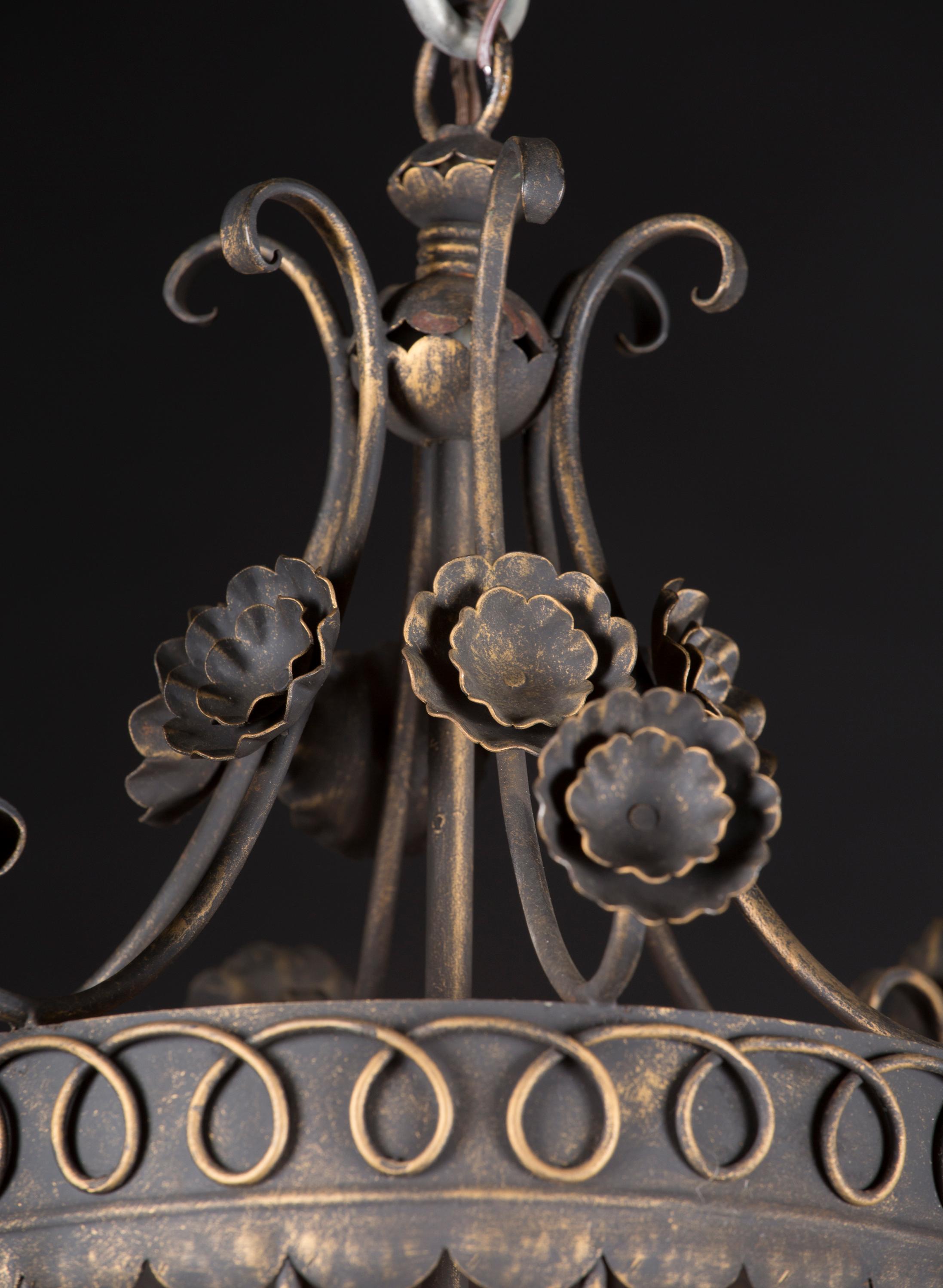 This beautiful French patinated iron lantern dates back to the mid 20th century. The top features scroll work, descending to the lantern body through outreaching flowers. The body itself is detailed with simple pattern work, as well as vines with