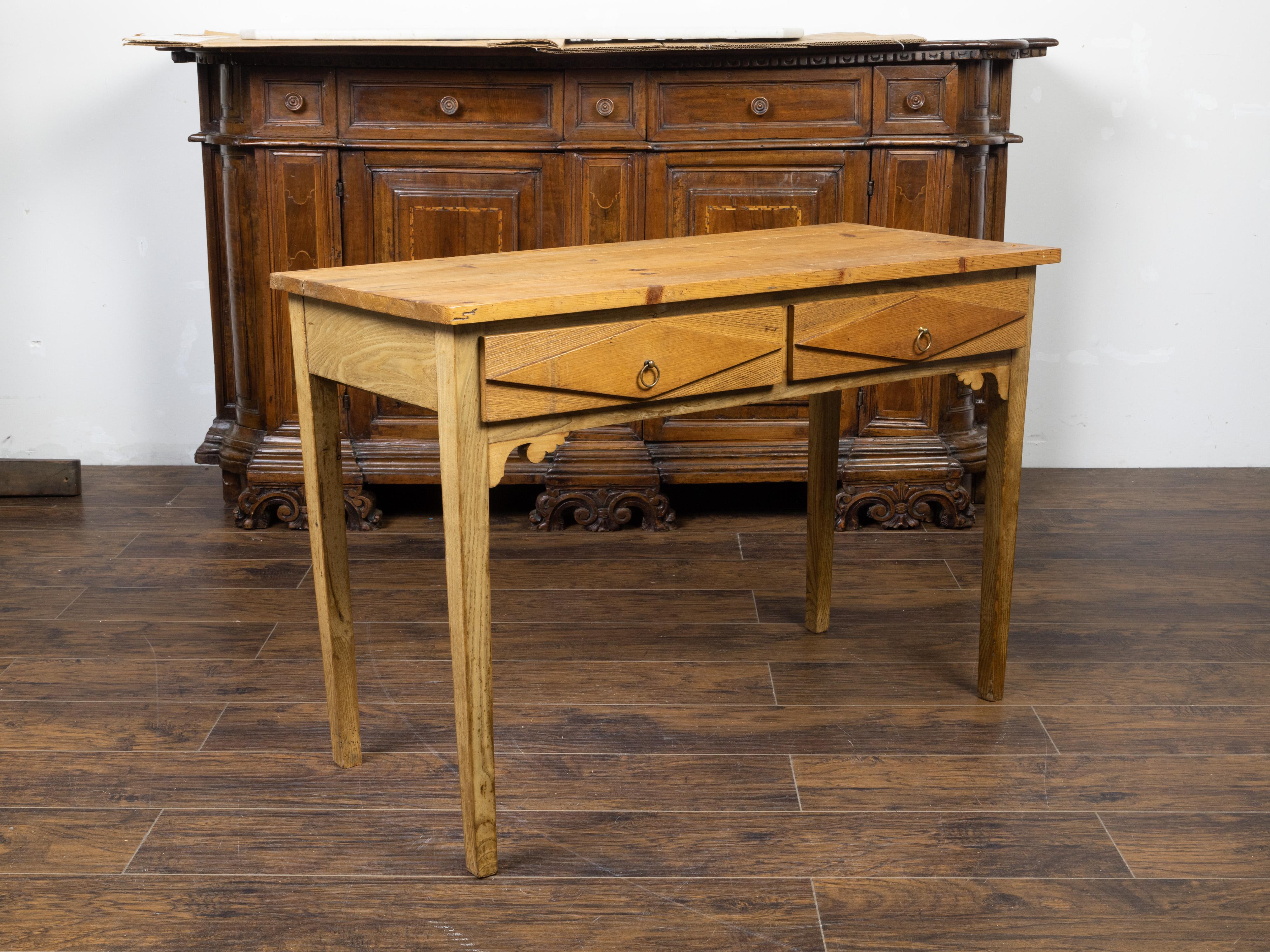 A French pine desk from the 20th century, with two drawers and diamond motifs. Created in France during the 20th century, this pine desk features a rectangular planked top sitting above two drawers each adorned with raised diamond motifs and fitted