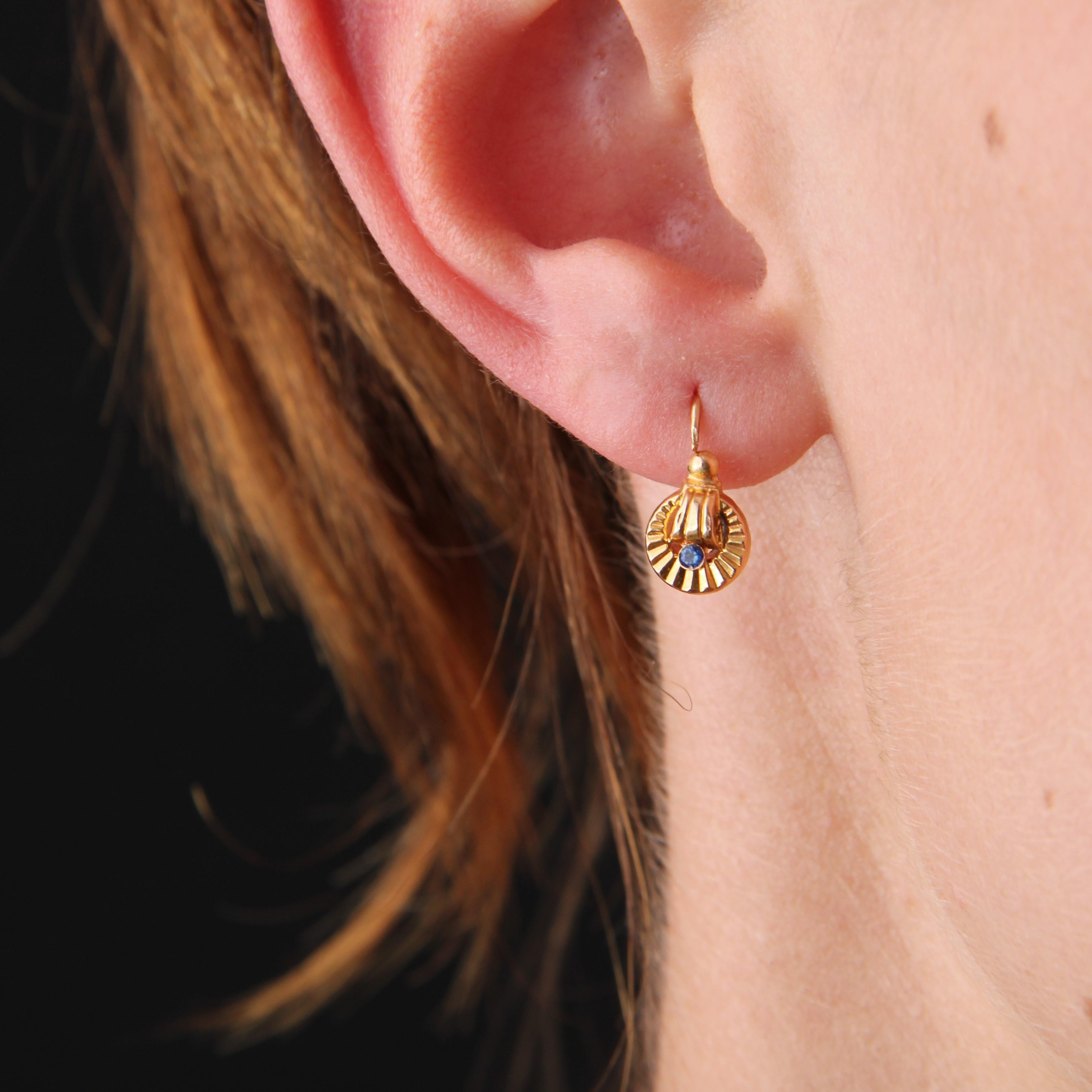 For pierced ears.
Earring in 18 karat rose gold, eagle head hallmark.
A pair of antique gold earrings, forming a striated gold circle topped with a gadrooned decoration and a gold pearl. The center is set with a sapphire. The clasp threads through