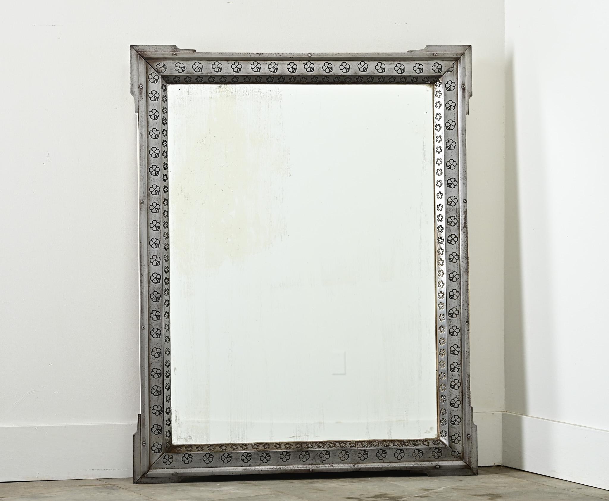 Uno specchio francese piuttosto unico degli inizi del XX secolo, composto da una cornice in acciaio con icone di quadrifoglio e fiori stilizzati in rilievo, montata su un involucro di legno a mo' di finestra. Ogni angolo è definito da flange