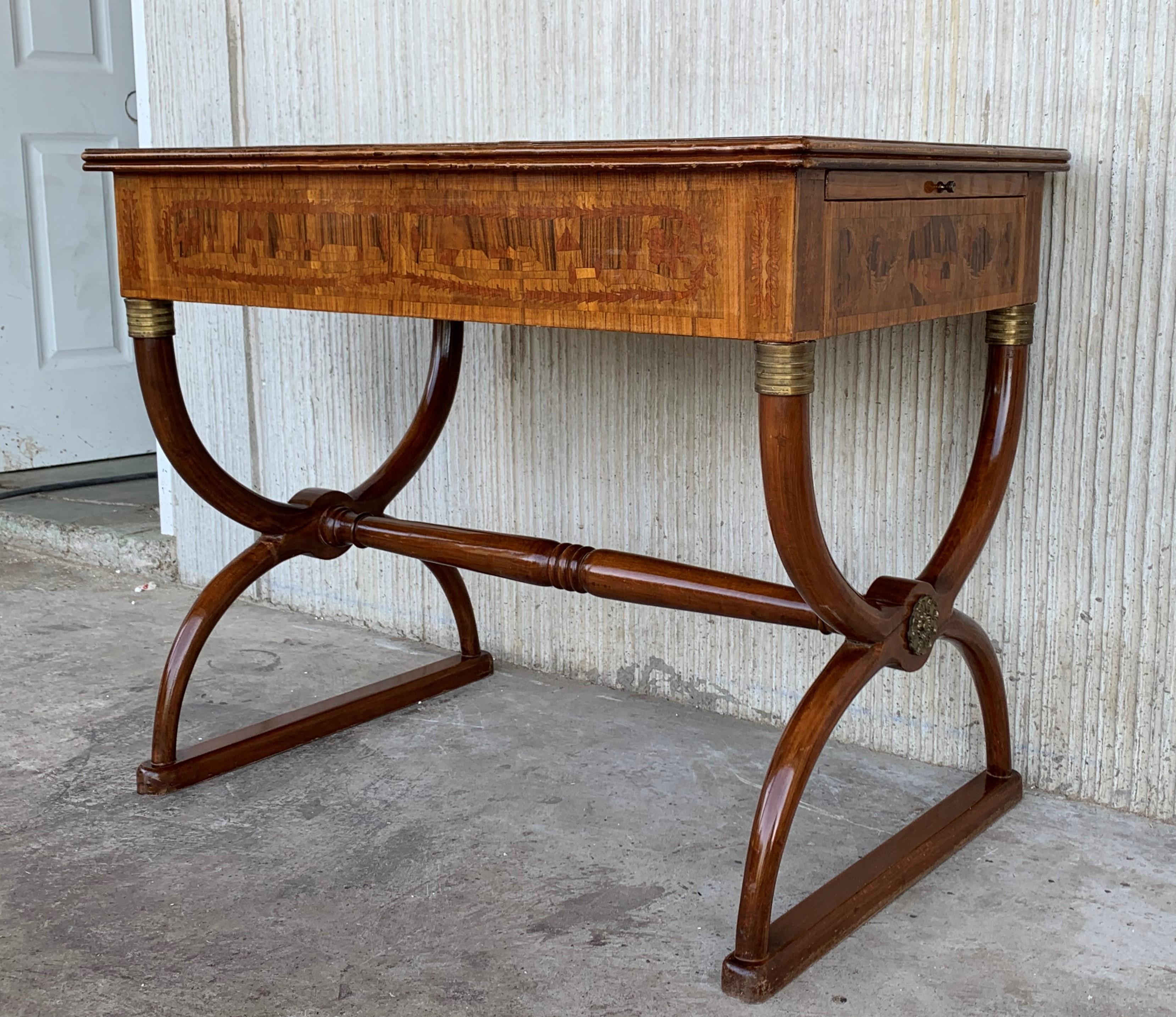 An elegant writing table in the Charles X style, 20th century. The top is adorned with an foliate marquetry. The belt, decorated with thin stylized ornaments and three drawers, unveils a sliding writing surface in both sides with marquetry